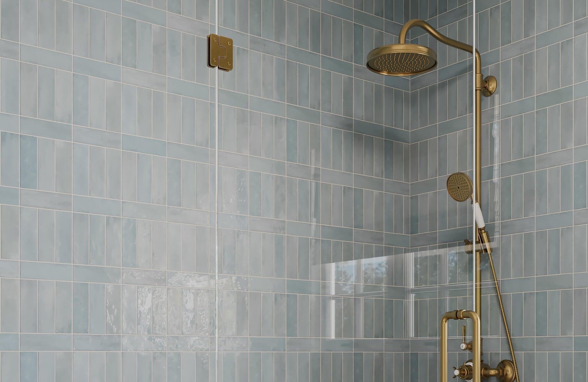 Glossy soft blue subway tiles in a mixed vertical and horizontal layout, paired with brushed brass shower fixtures.