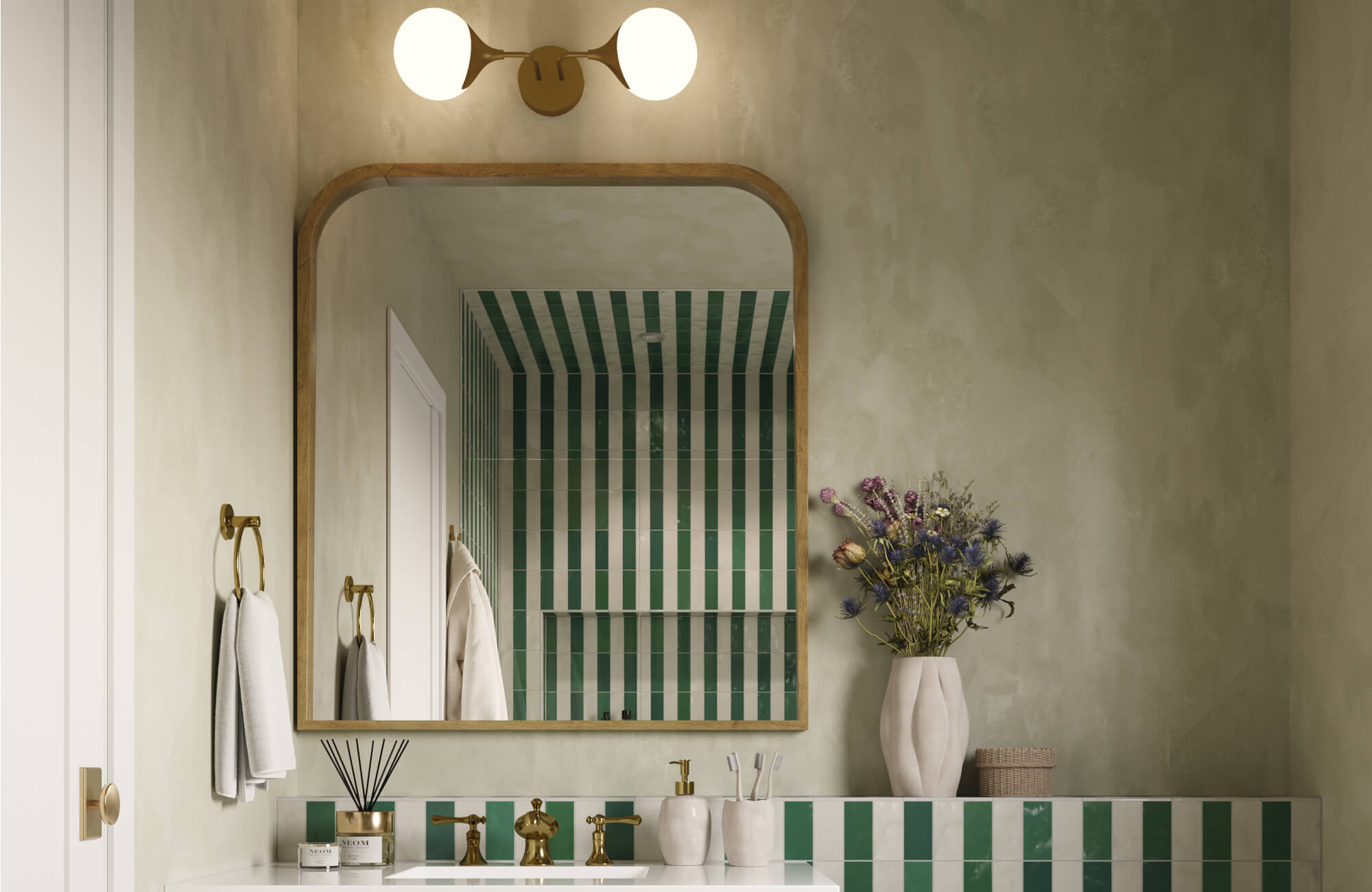 Bathroom with vertical green and white striped tiles, a rounded-edge mirror, brass fixtures, and a double globe wall sconce.