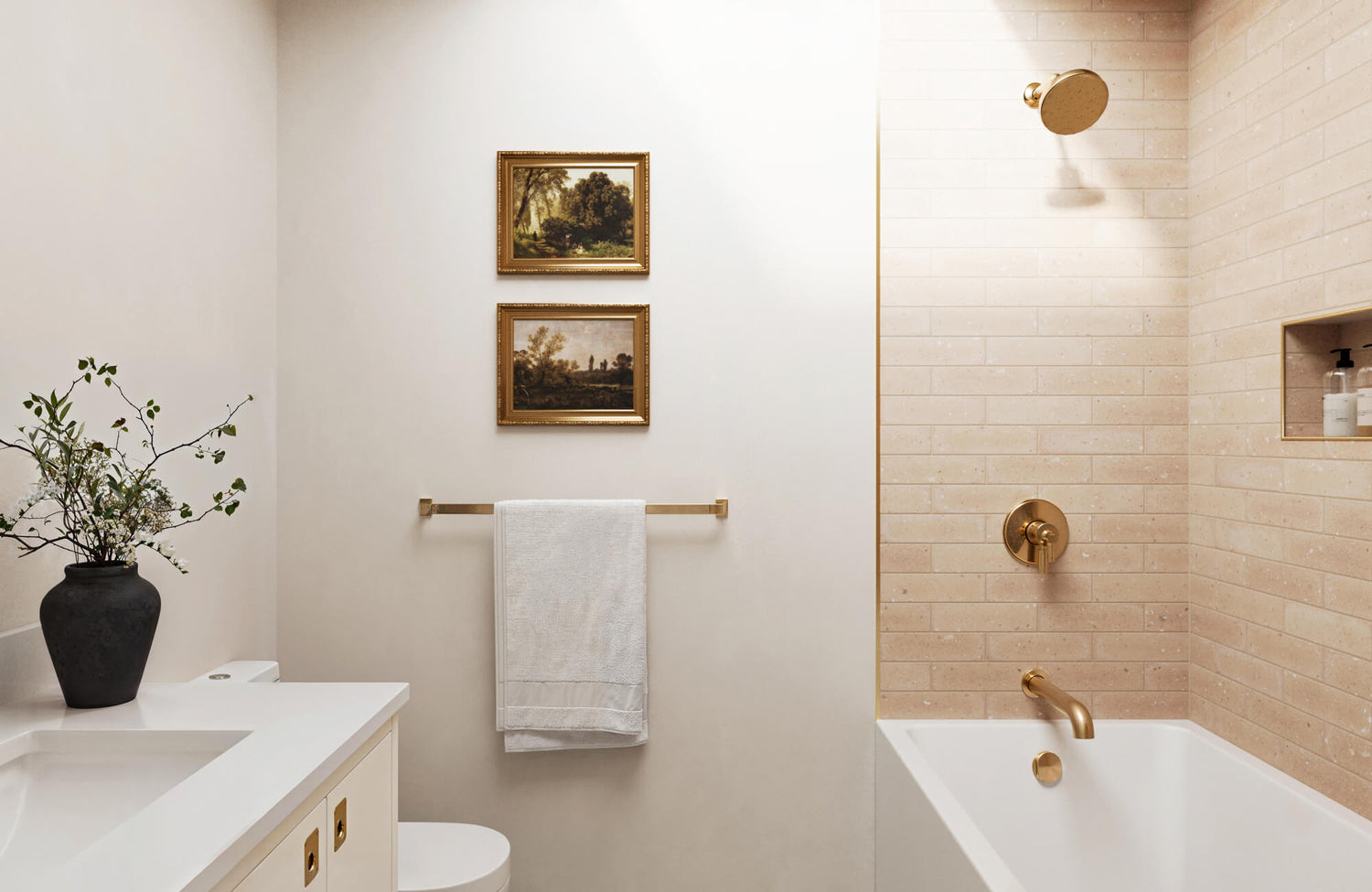Warm beige subway tiles complement brass fixtures in this elegant bathroom, featuring a sleek white vanity and framed vintage artwork.
