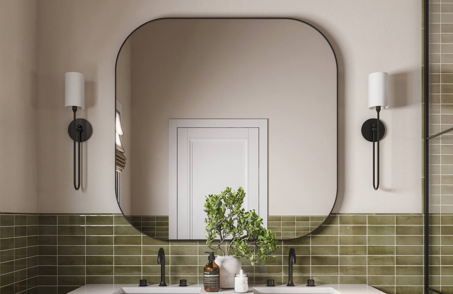 Modern bathroom vanity with a soft-cornered mirror and matte black fixtures, set against olive green subway tile and minimalist neutral walls.
