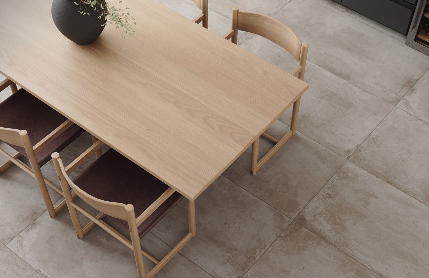 Dining room with large cement-look floor tiles creating a smooth, modern foundation under a wooden table and chairs.
