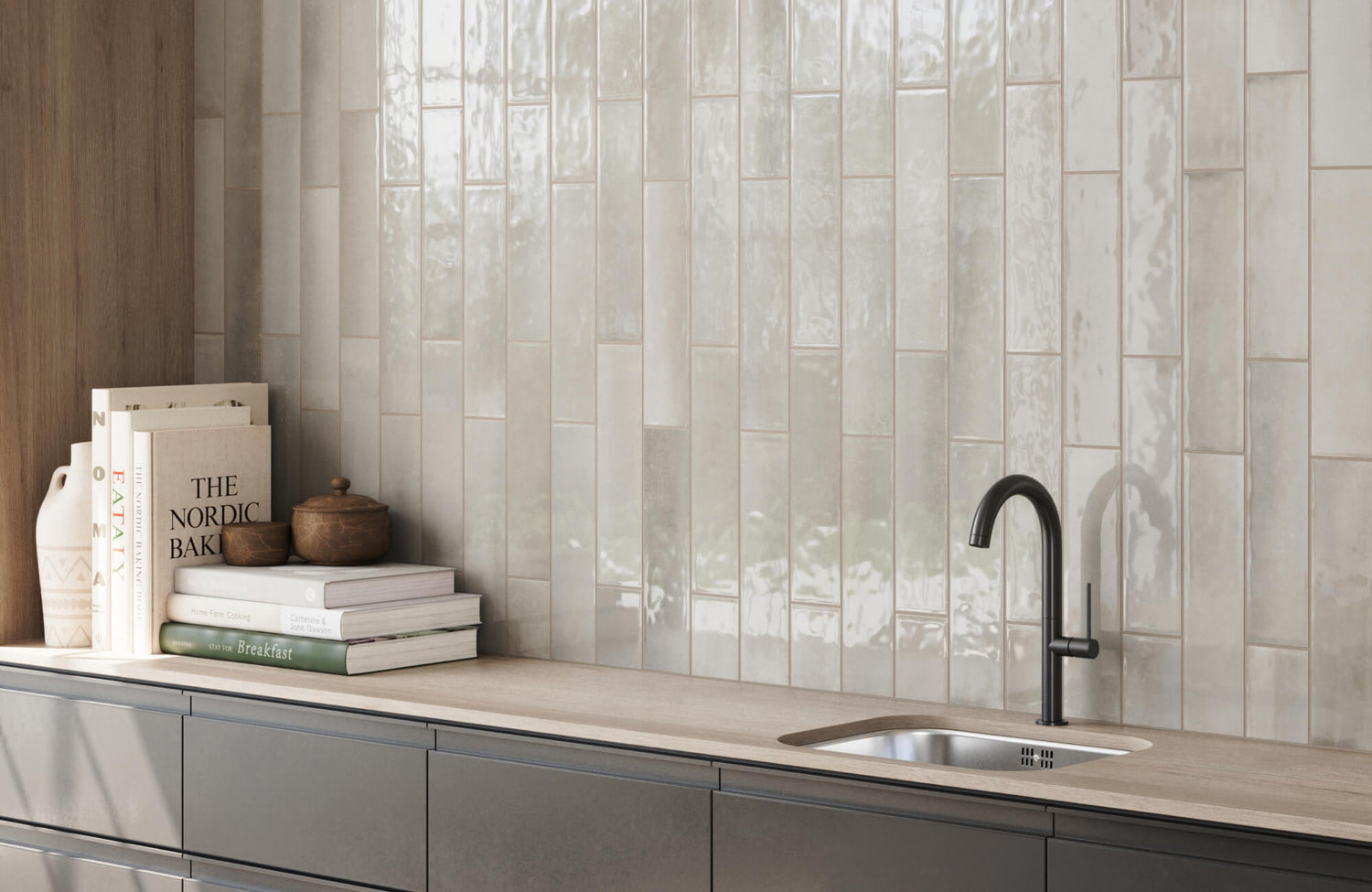 Modern kitchen backsplash featuring glossy, vertically stacked subway tiles in soft neutral tones, complementing wood and matte black accents.