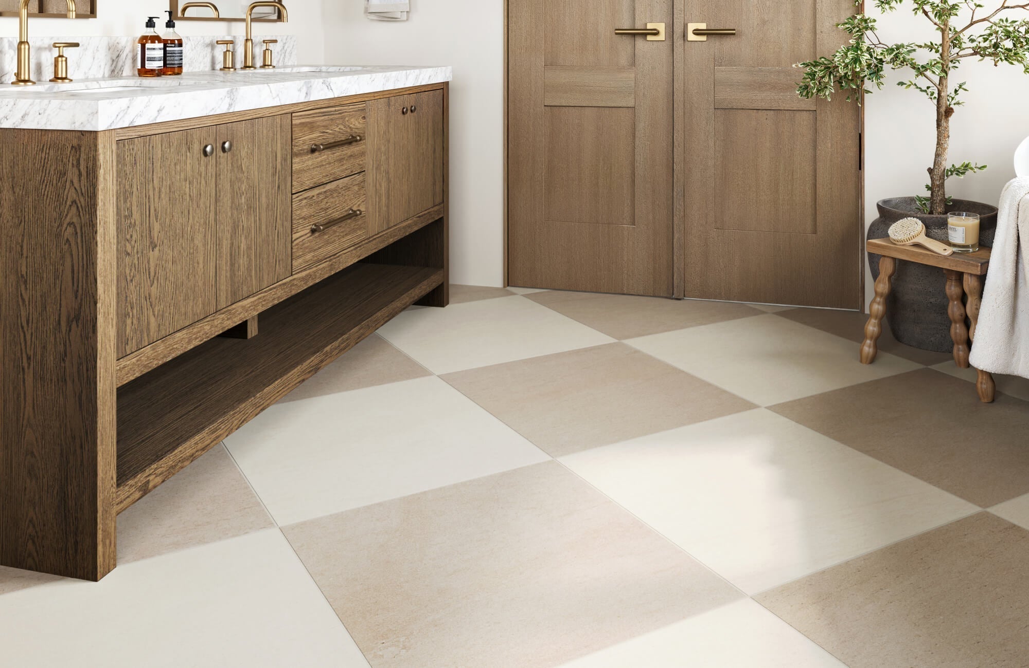 Bathroom interior with beige and cream chequered porcelain floor tiles, wood vanity, and gold fixtures.