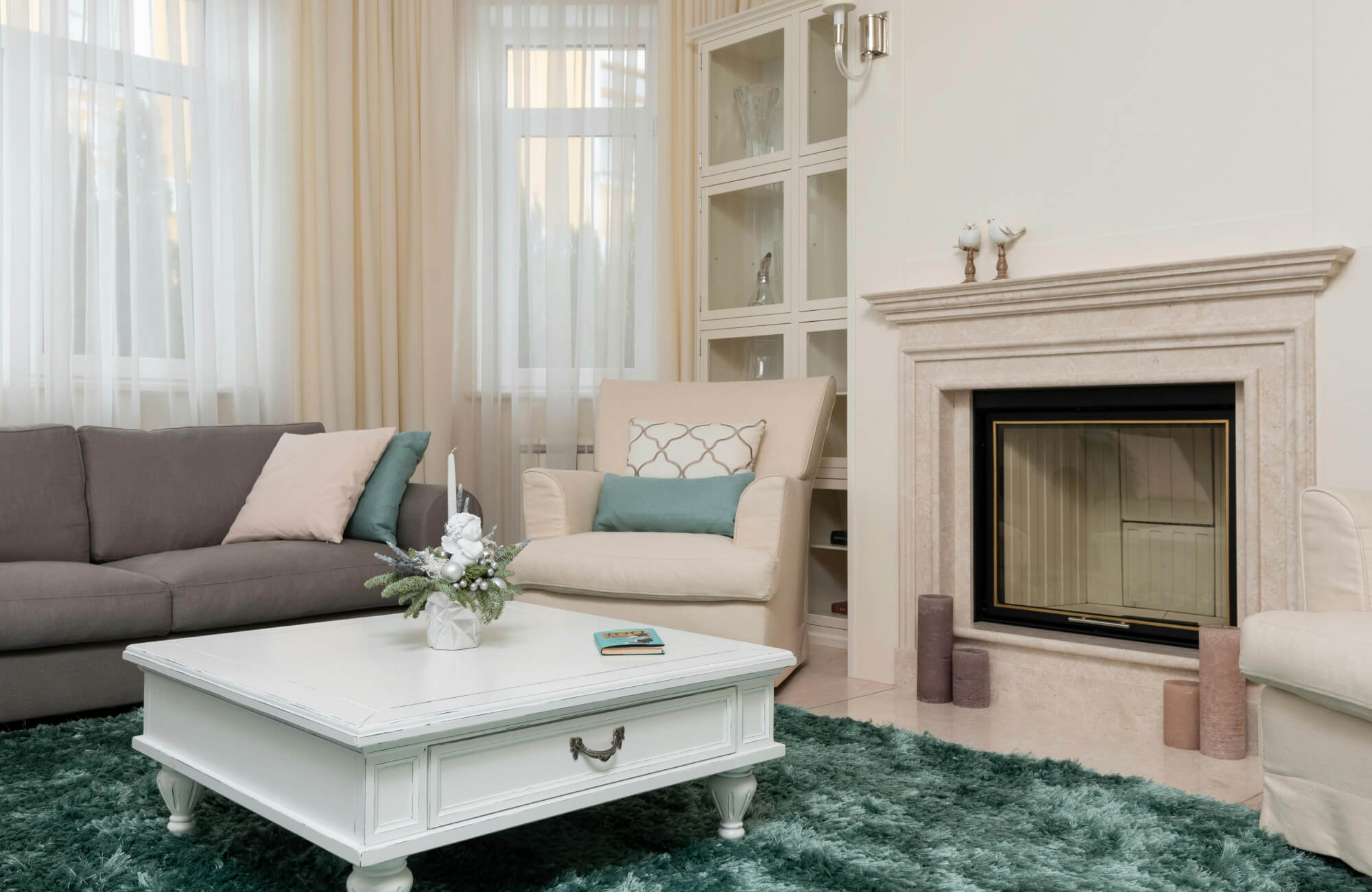 A plush, deep green rug adds warmth and texture to a neutral living room with beige and gray furniture.
