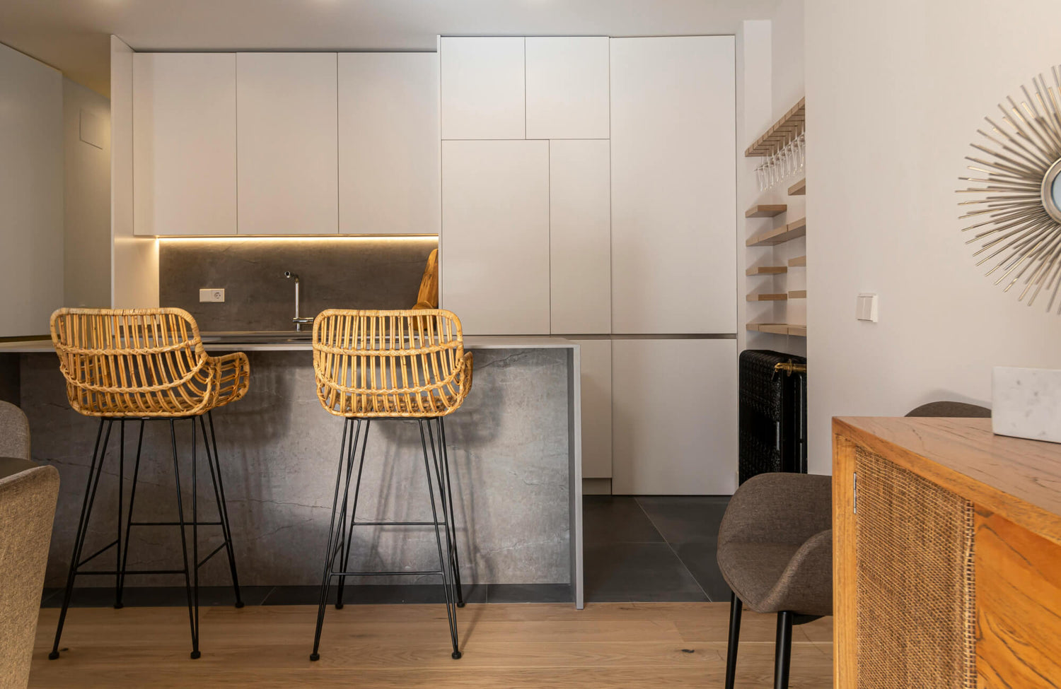 Wicker bar stools with open woven seats add warmth and texture to a modern kitchen island with clean lines and neutral finishes.