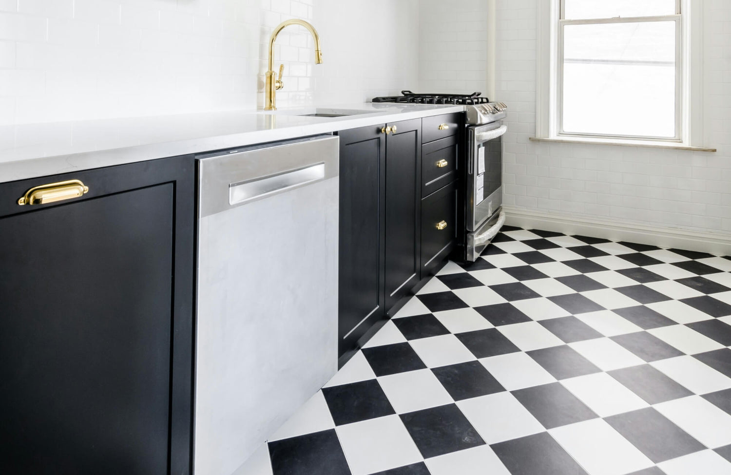 Classic black and white checkered kitchen floor tiles paired with sleek black cabinetry and gold accents for a modern look.