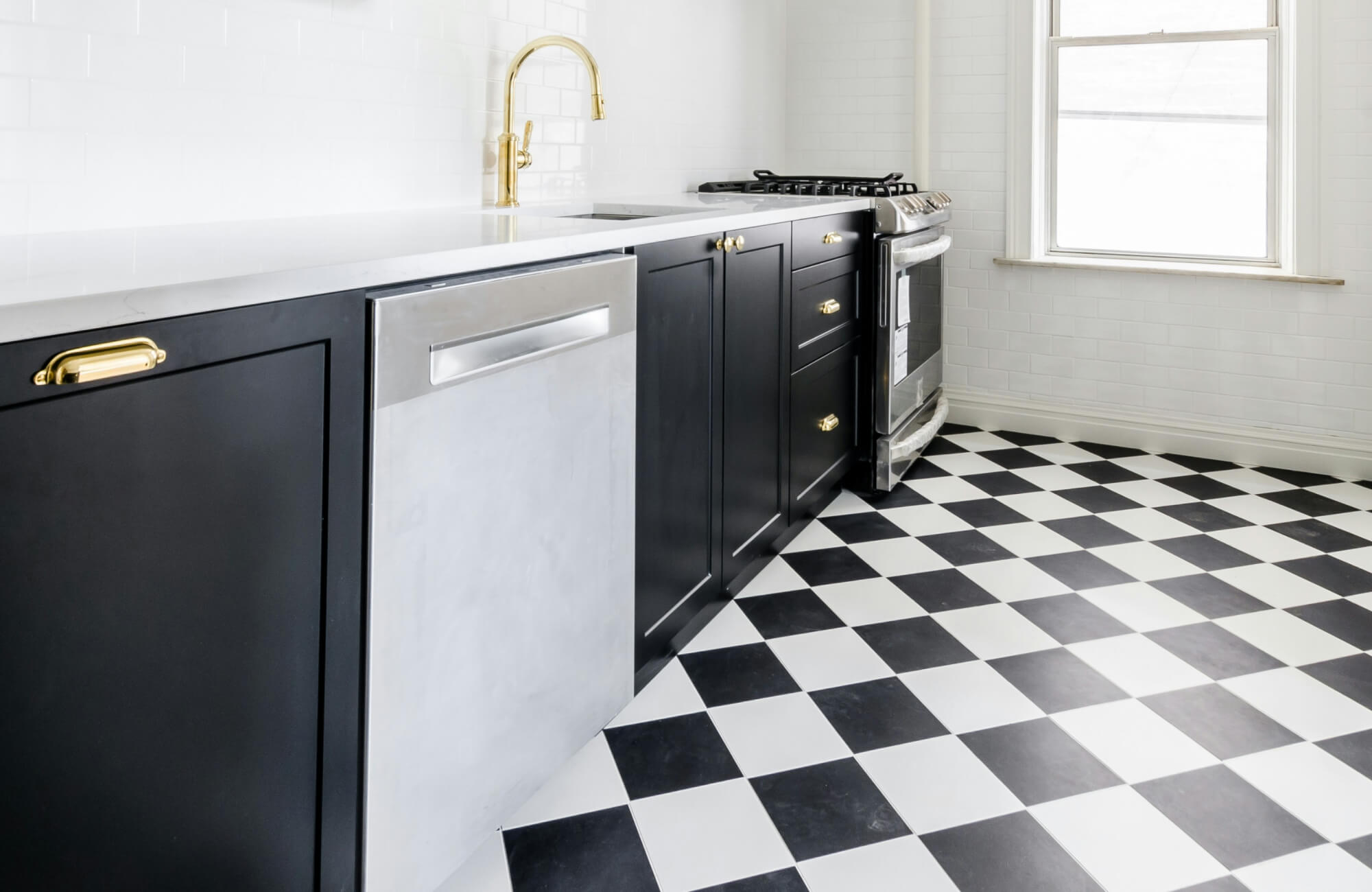 Classic black and white checkered kitchen floor tiles paired with sleek black cabinetry and gold accents for a modern look.