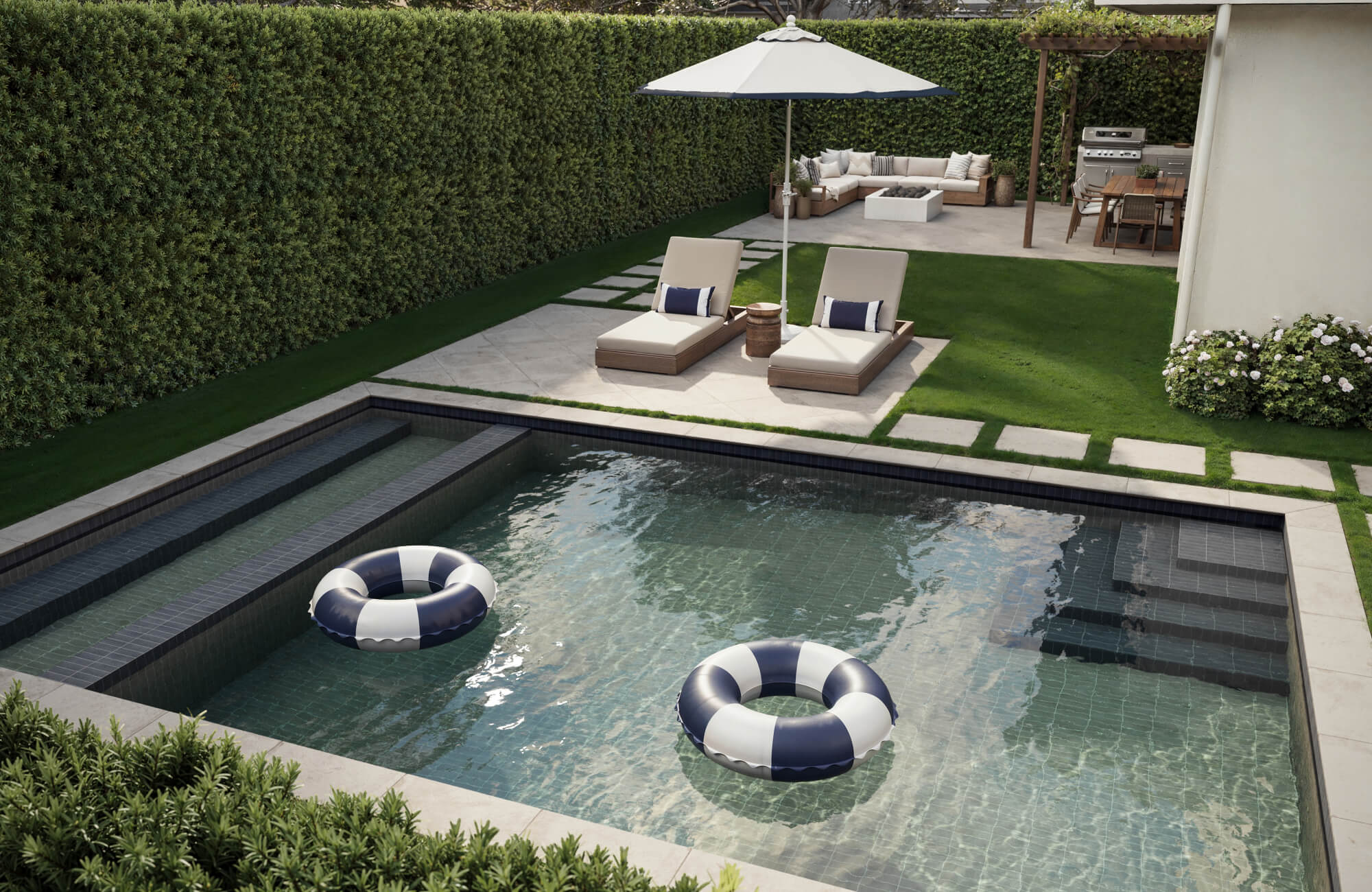 Modern backyard with a tiled plunge pool, striped float rings, lounge chairs, and outdoor seating under a pergola.