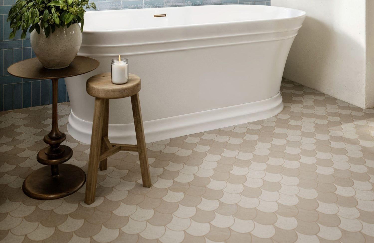 Beige and white scallop-pattern mosaic tile flooring in a bathroom with a freestanding tub and blue tiled accent wall.