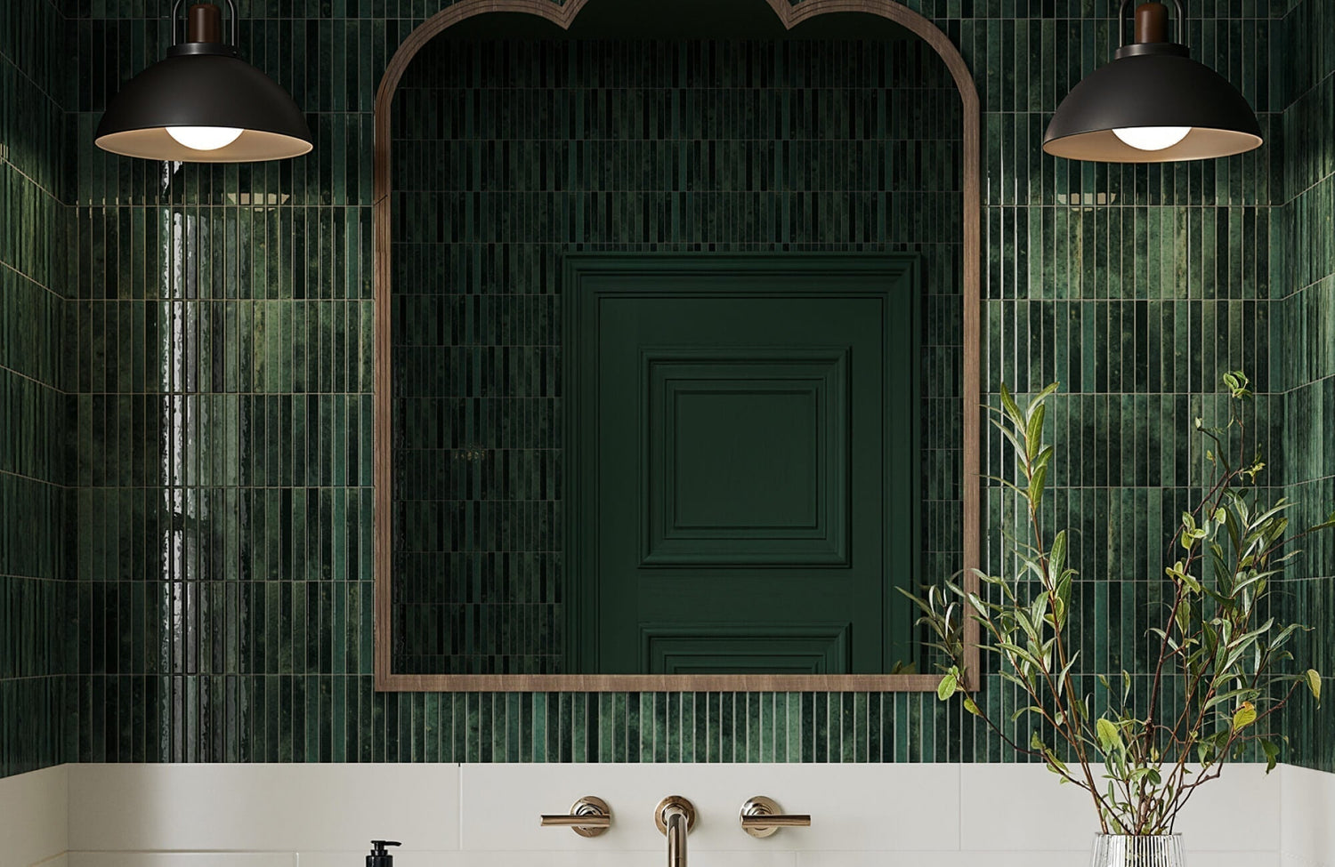 Sleek matte black wall sconces with dome shades cast a warm, focused glow over a deep green tiled wall, enhancing the moody elegance of the space.