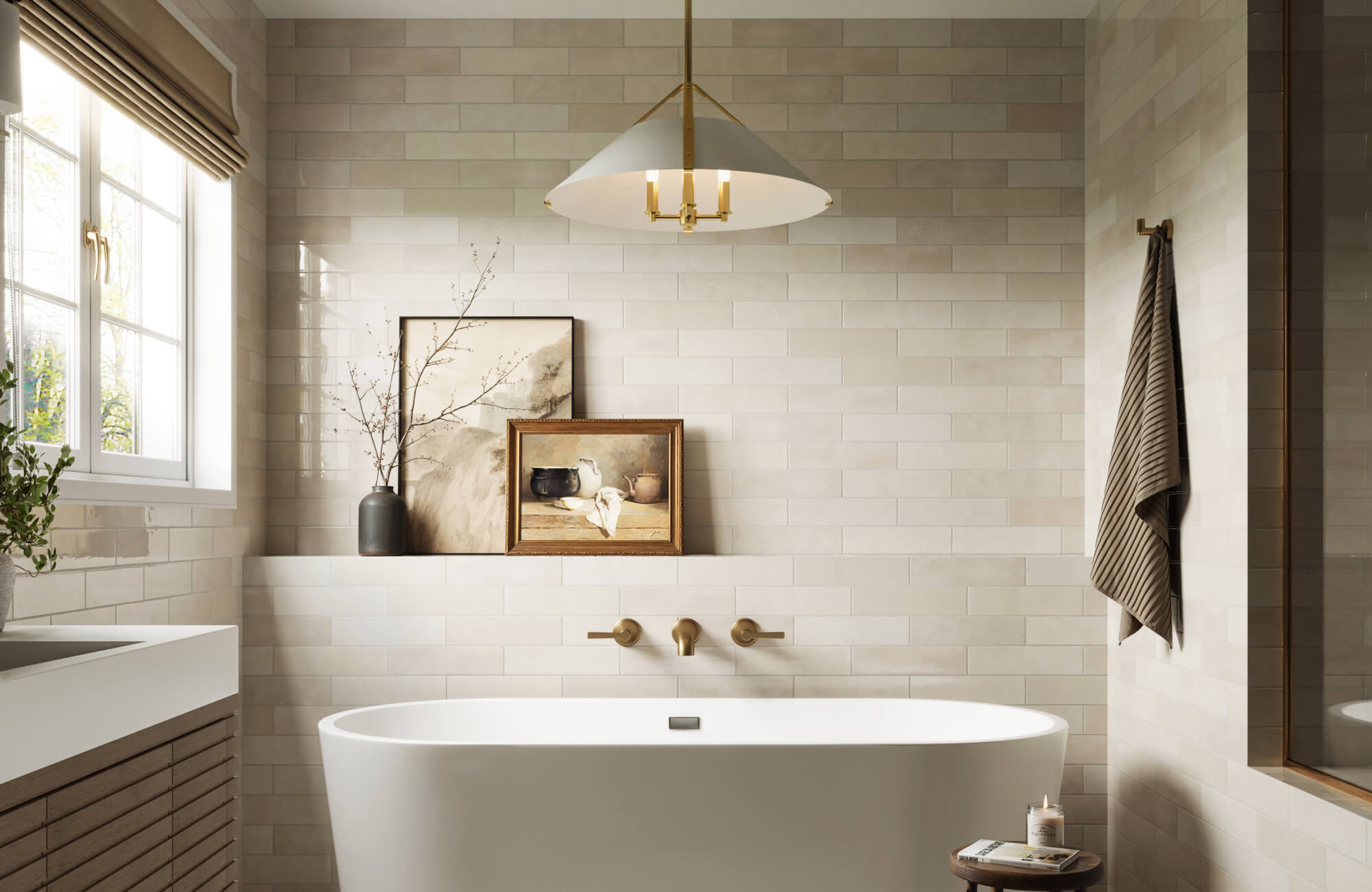 Serene bathroom with a freestanding white tub, beige subway tile walls, gold wall-mounted fixtures, and soft natural lighting from a nearby window.