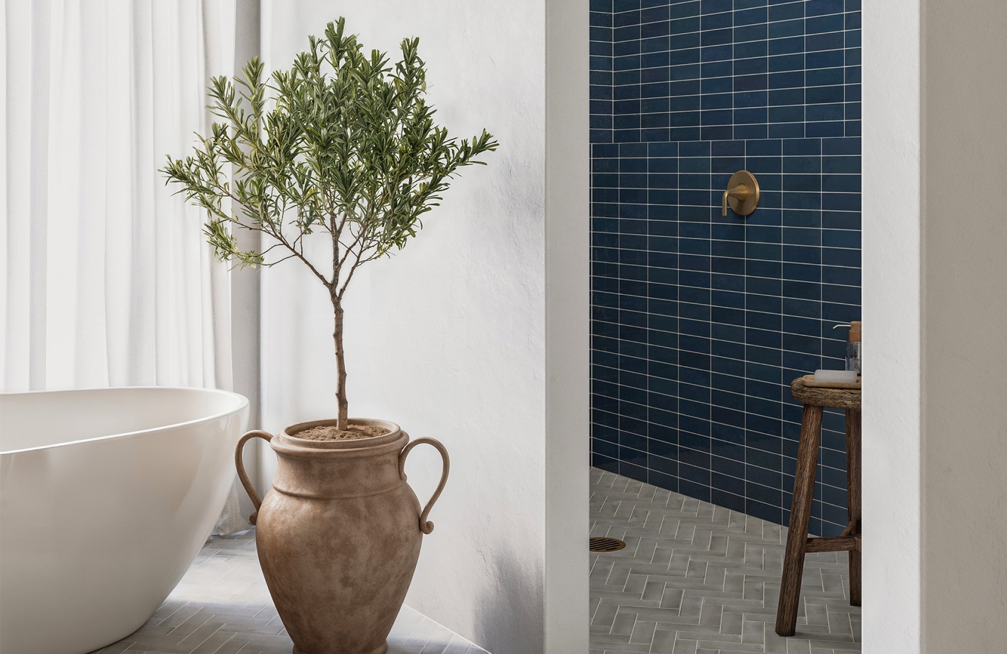 Dark blue shower tiles paired with neutral-toned herringbone flooring and natural terracotta decor for a warm, earthy contrast.