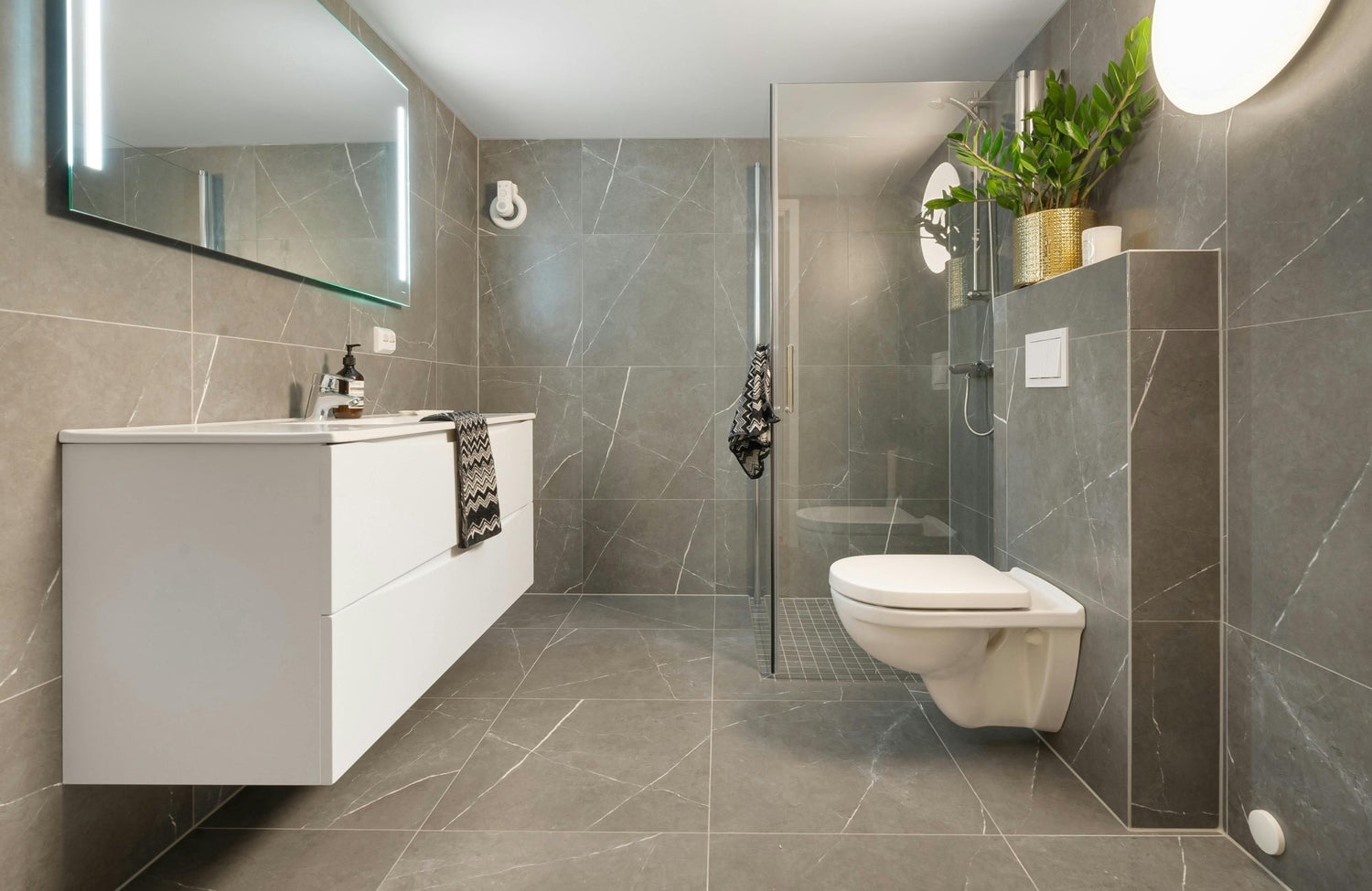 Modern bathroom with grey marble tiles and a sleek white vanity for a crisp, high-contrast color combination.