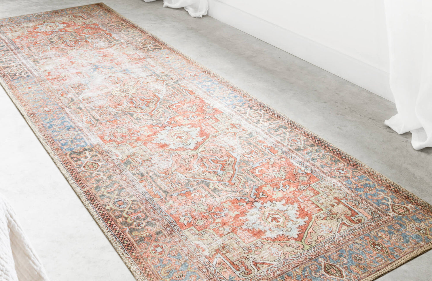 Warm-toned vintage-style rug in coral, ivory, and blue hues adds instant coziness and charm to this bright minimalist room