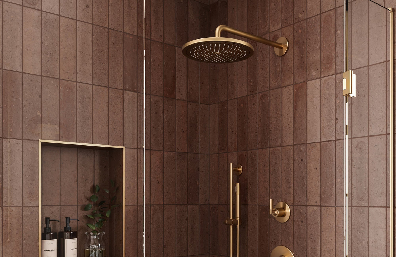 Walk-in shower featuring vertical matte brown ceramic tiles, brushed brass rain showerhead, matching fixtures, and built-in niche shelving