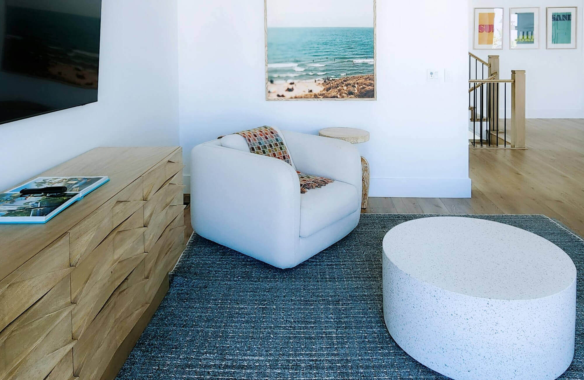 Living room with a textured blue rug paired with neutral furniture and light wood tones for a fresh coastal-inspired look.
