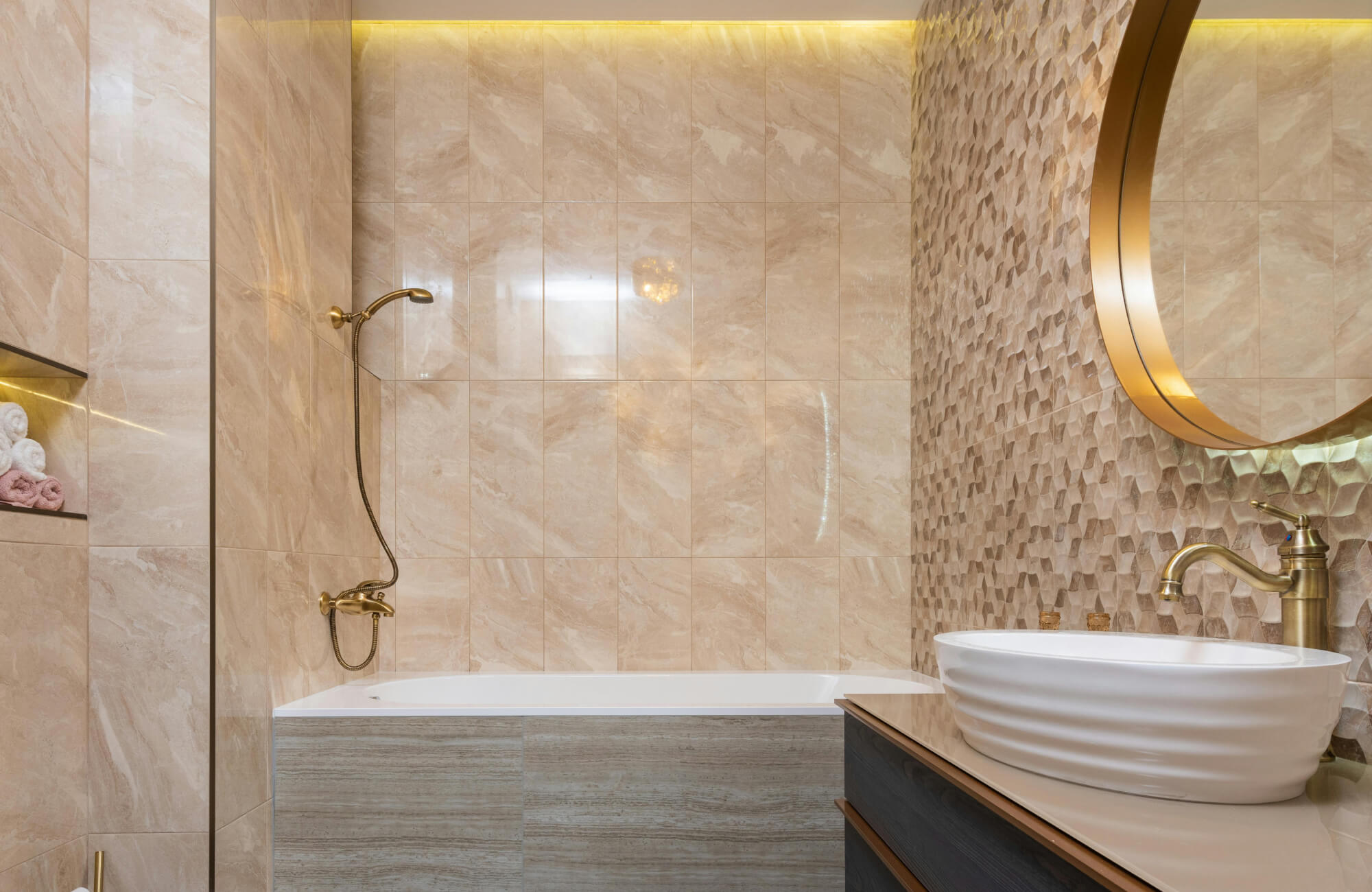 Modern beige marble bathroom wall tiles with built-in tub, sculpted accent wall, and brushed gold fixtures in warm golden tones