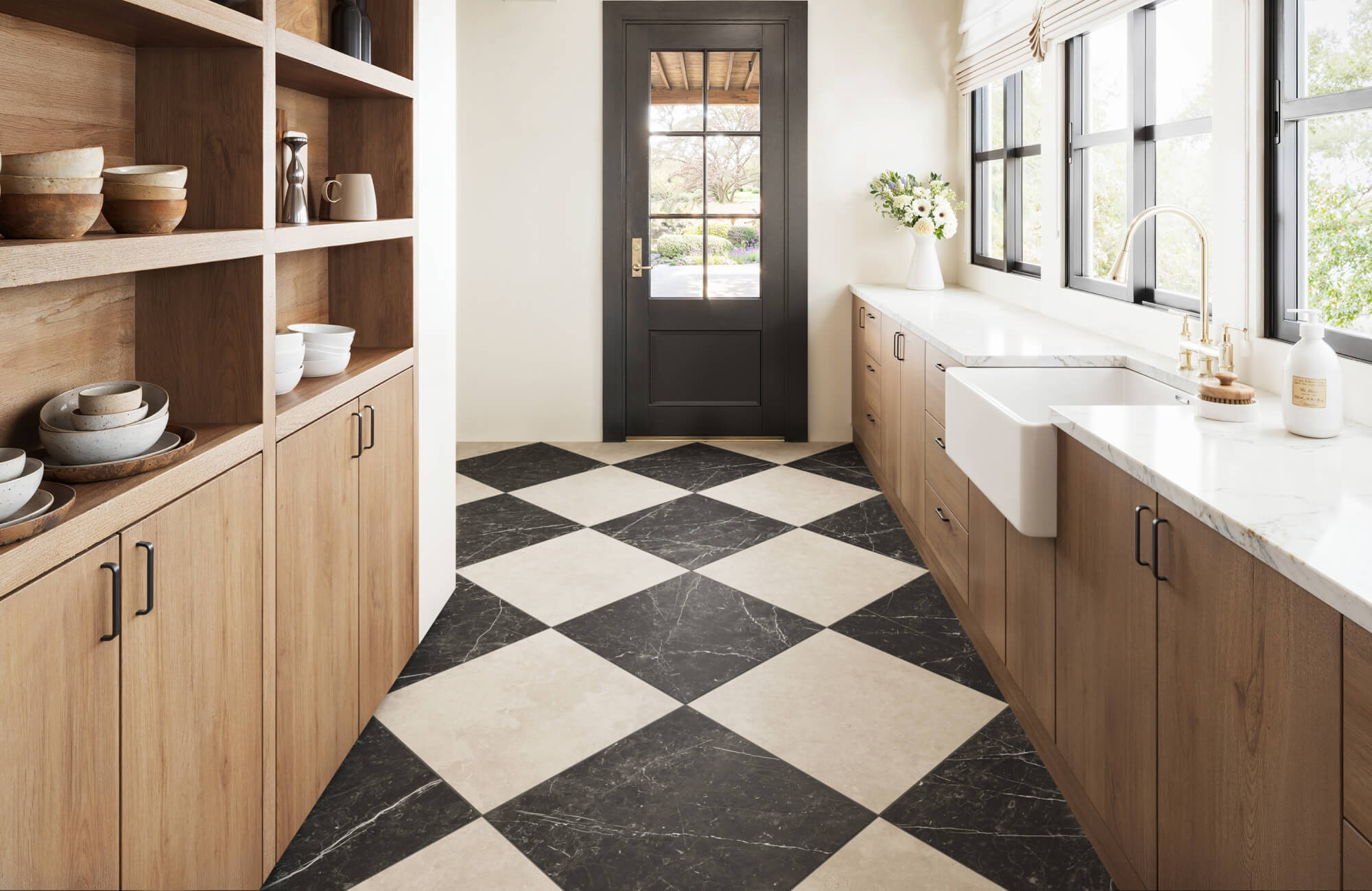 Stylish kitchen with a bold black and white checkered marble floor, warm wood cabinetry, and elegant brass fixtures.