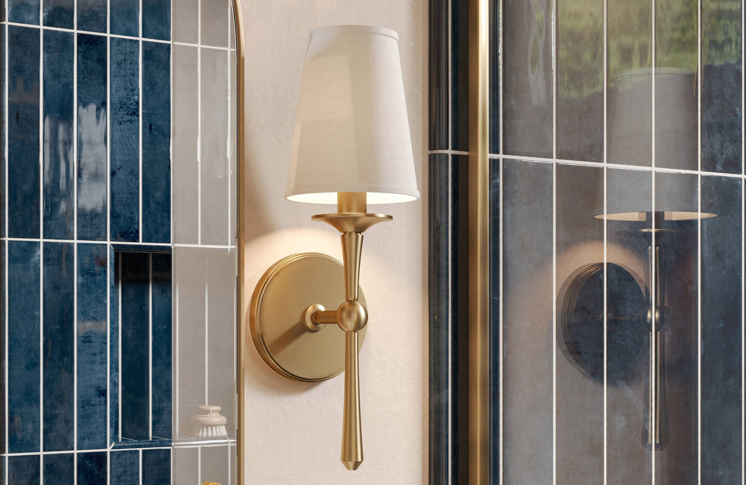 Elegant brass wall sconce with tapered fabric shade, set beside glossy navy vertical tile and mirror.
