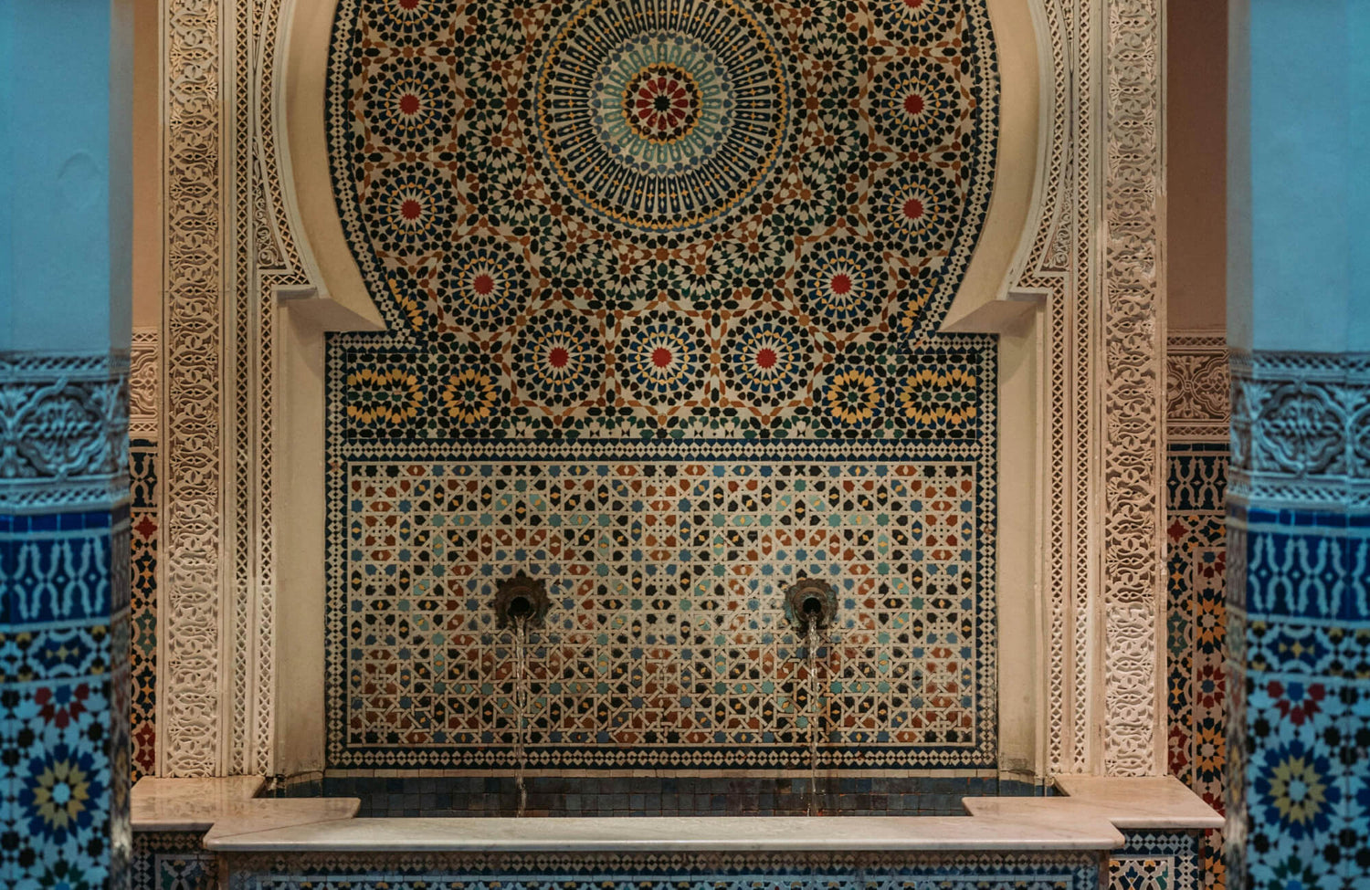 Intricate Moroccan mosaic fountain with multicolored Zellige tilework arranged in geometric patterns and radial medallions.