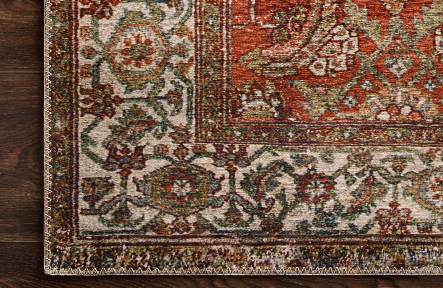 Close-up of Oriental rug with intricate floral patterns in earthy red, green, and beige tones.