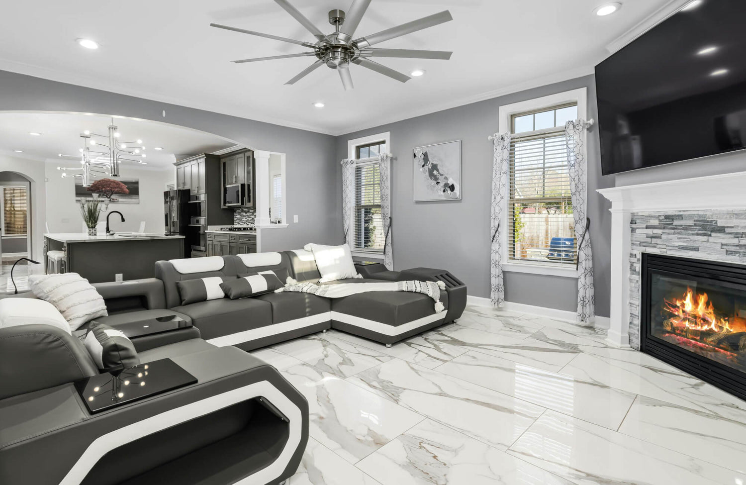 Modern living room with glossy marble-look tile flooring, a sleek sectional sofa, and a cozy fireplace, blending luxury with comfort.