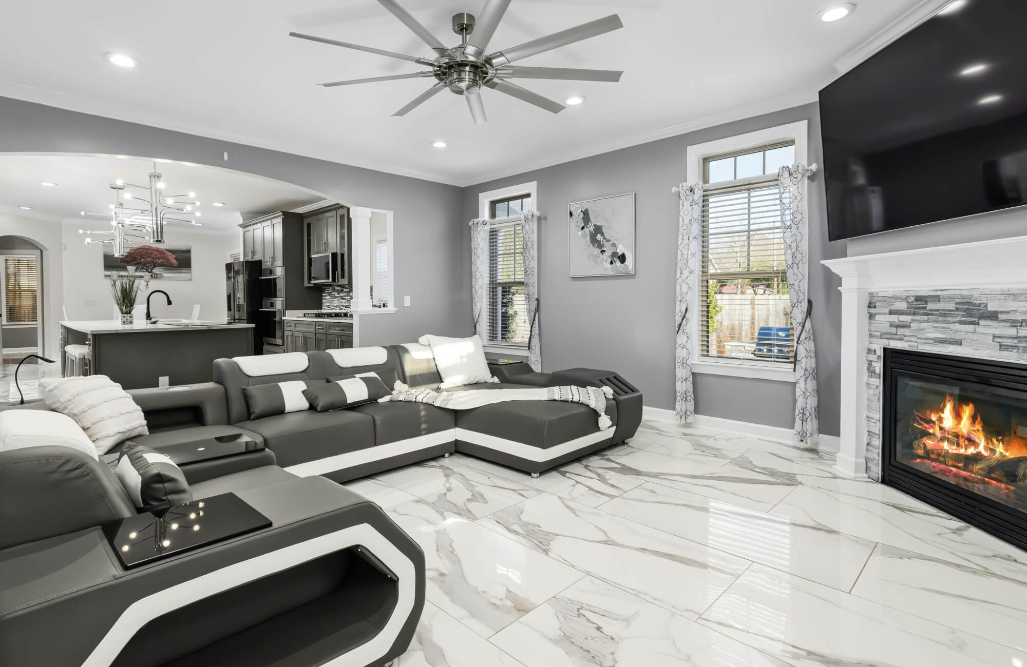 Modern living room with glossy marble-look tile flooring, a sleek sectional sofa, and a cozy fireplace, blending luxury with comfort.