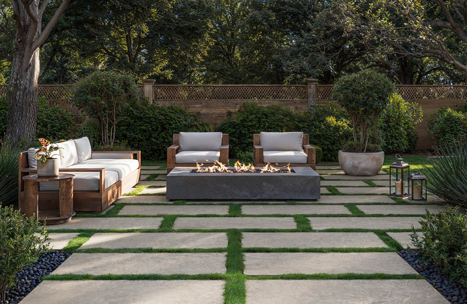 Landscaped backyard patio with wooden outdoor sofa and chairs around a fire feature, showing durable materials suited for sun and seasonal weather exposure