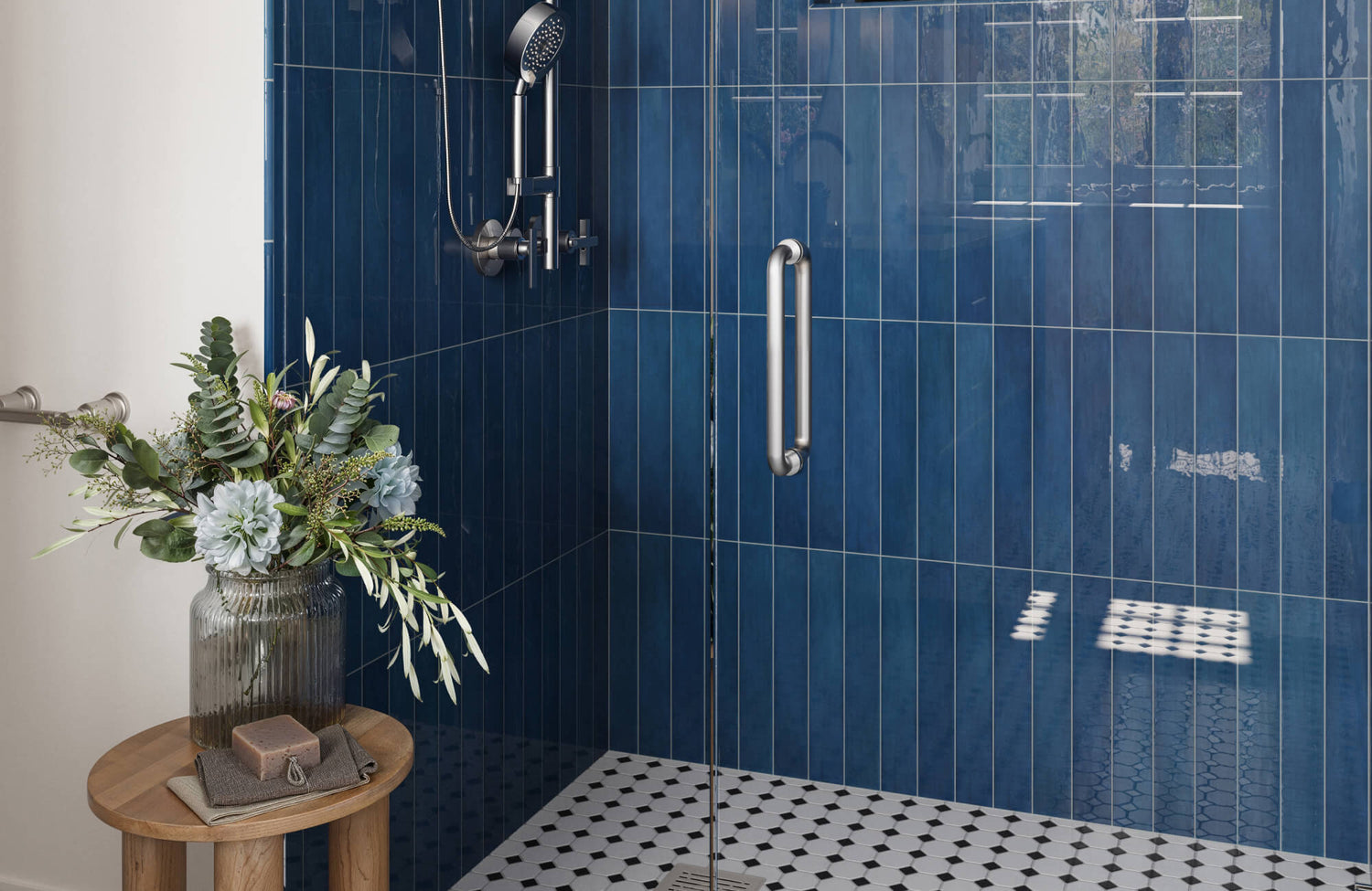 Modern shower featuring glossy deep blue vertical subway tiles on the wall and classic white hexagon floor tiles with black accents.