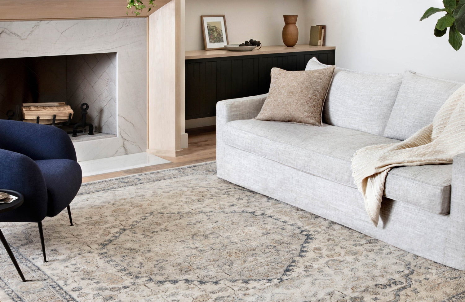 Neutral beige and gray rug in a soft-toned living room with a light stone fireplace and minimalist styling
