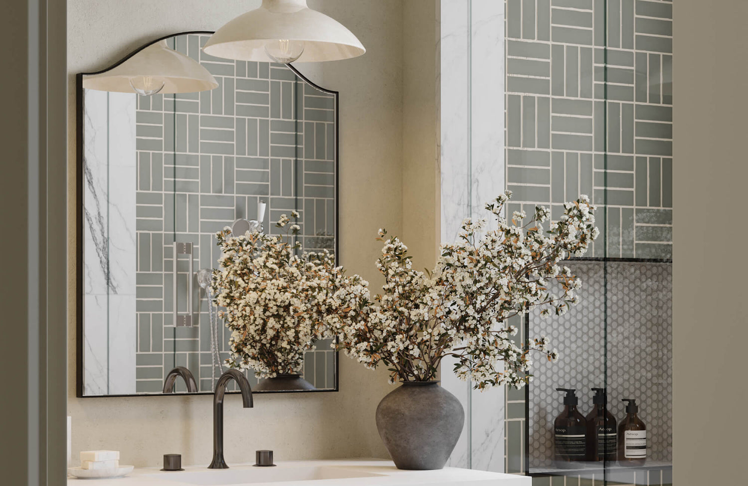 Elegant bathroom mirror with a sleek black frame reflects geometric green tile walls, complemented by a modern vanity, matte black faucet, and a vase of blooming branches for a fresh, sophisticated look.