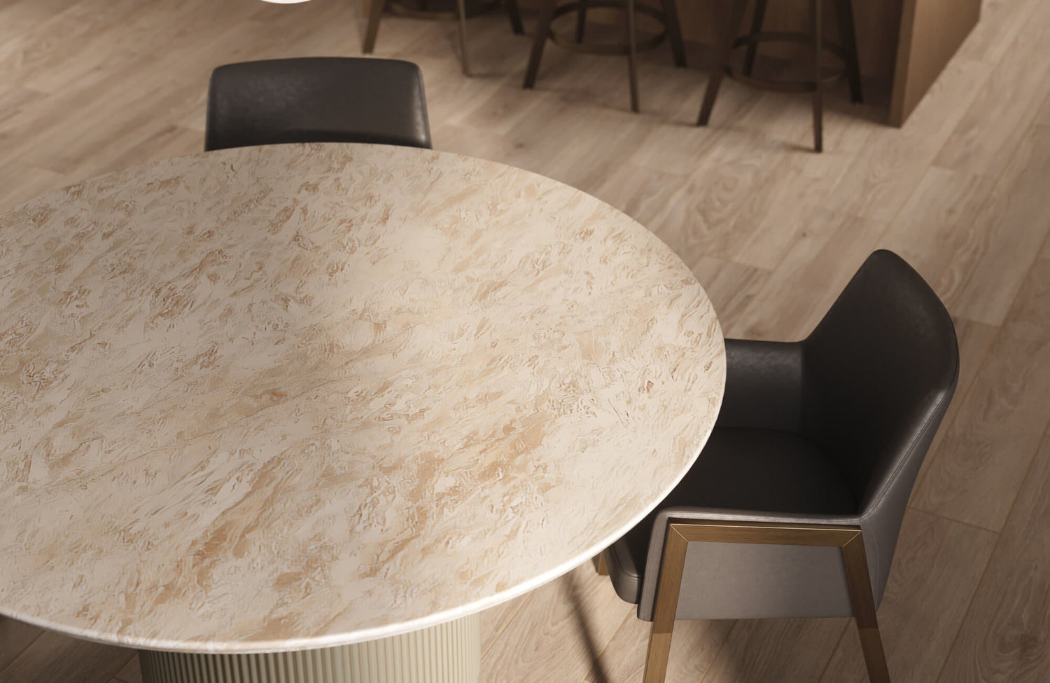 A round dining table with a light beige textured top, paired with a modern dark upholstered chair on warm wood flooring.