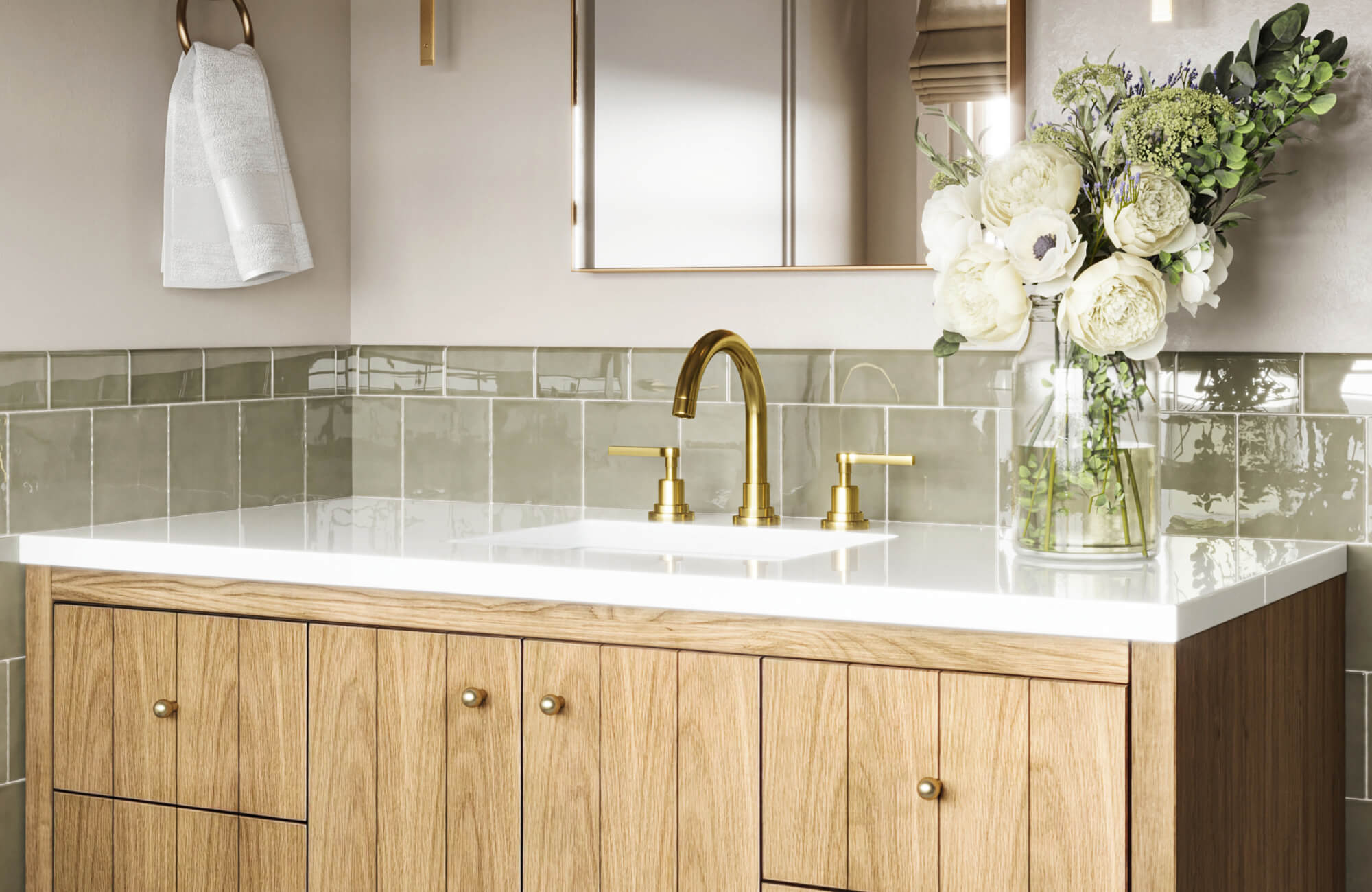 Glossy sage green subway tiles accent a bathroom backsplash above a white quartz vanity with oak cabinetry and brushed gold fixtures.