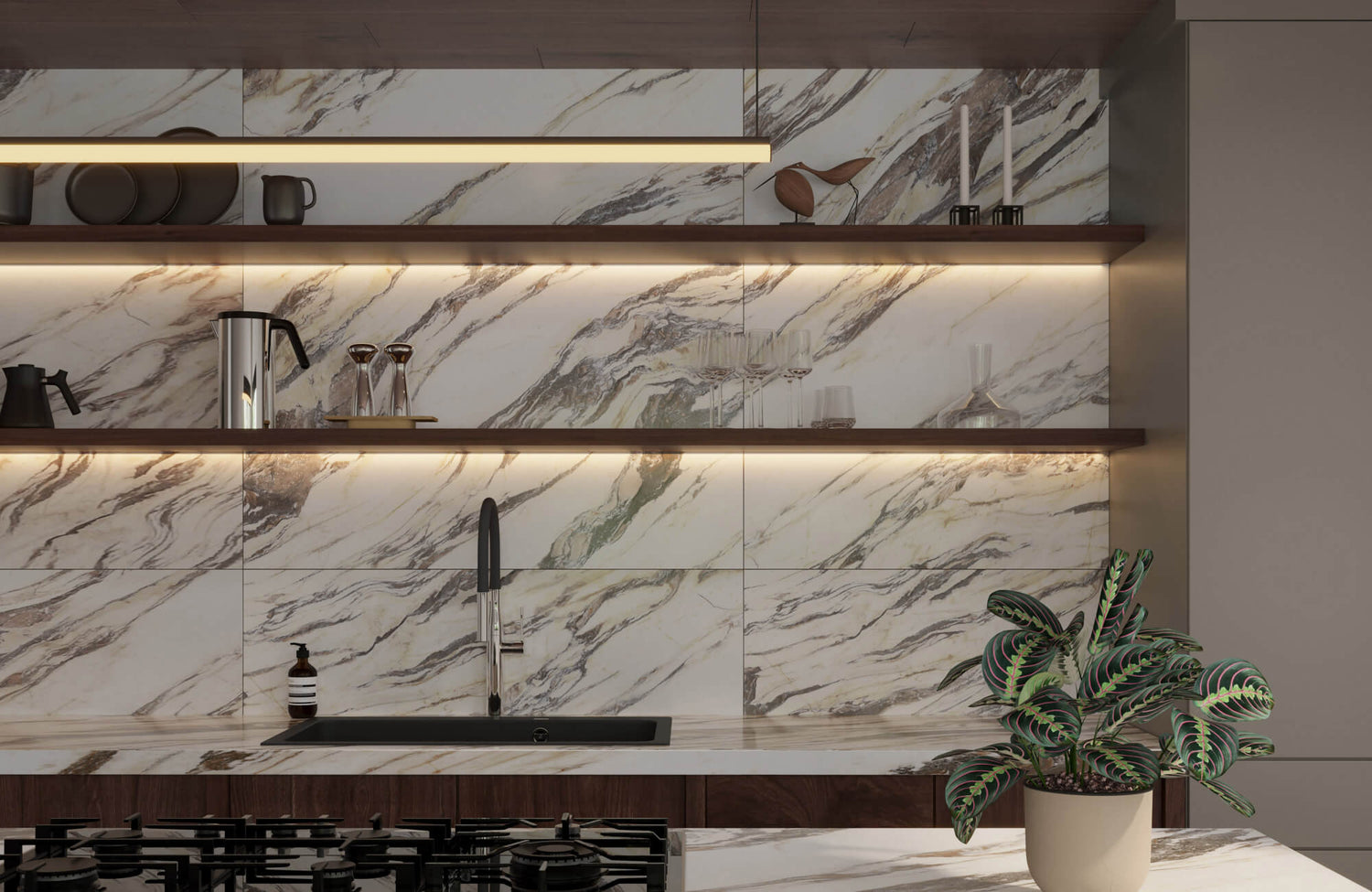 Modern kitchen with luxurious marble look tiles, warm under-shelf lighting, and sleek black fixtures complemented by a potted plant.