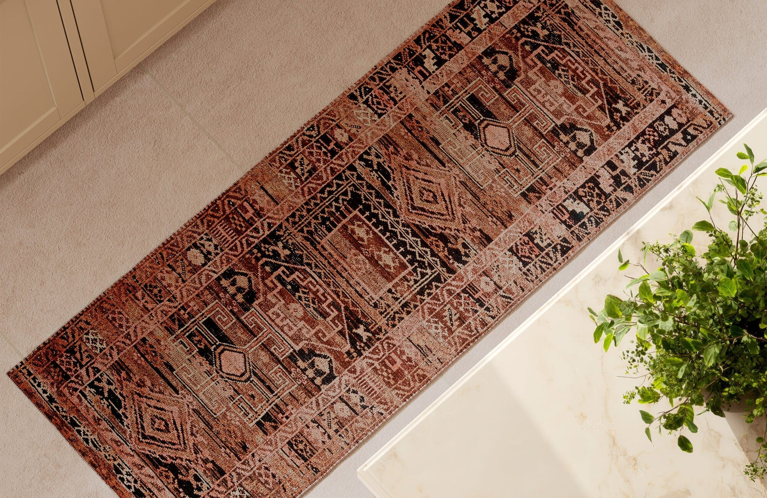 Luxury terracotta red and black runner rug with beige accents and geometric patterns in a modern kitchen with cream cabinetry and a marble countertop.