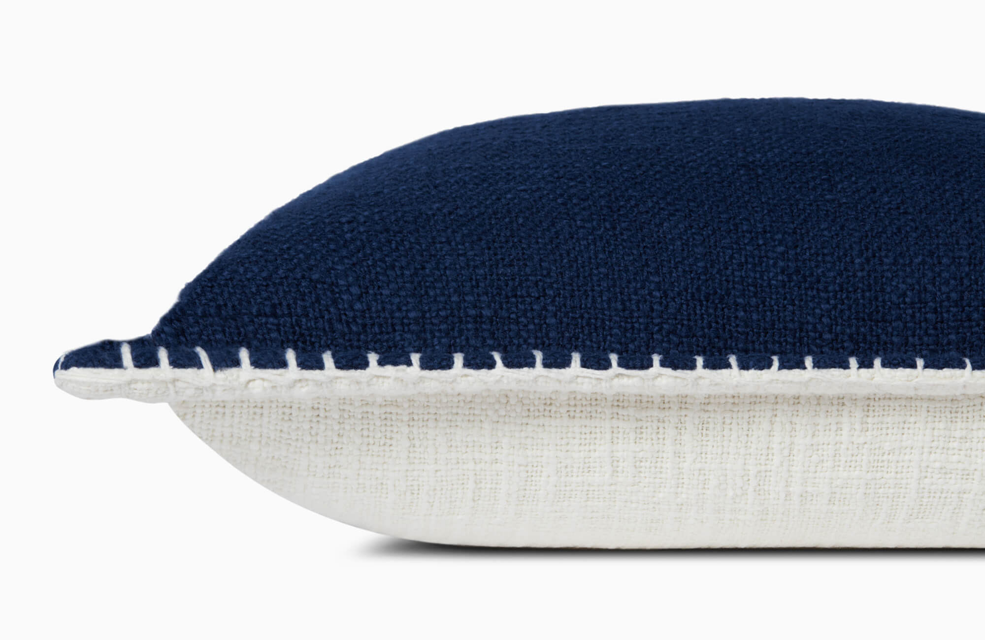 Two-tone throw pillow featuring deep blue boucle surface, natural linen underside, and visible white whipstitch trim.