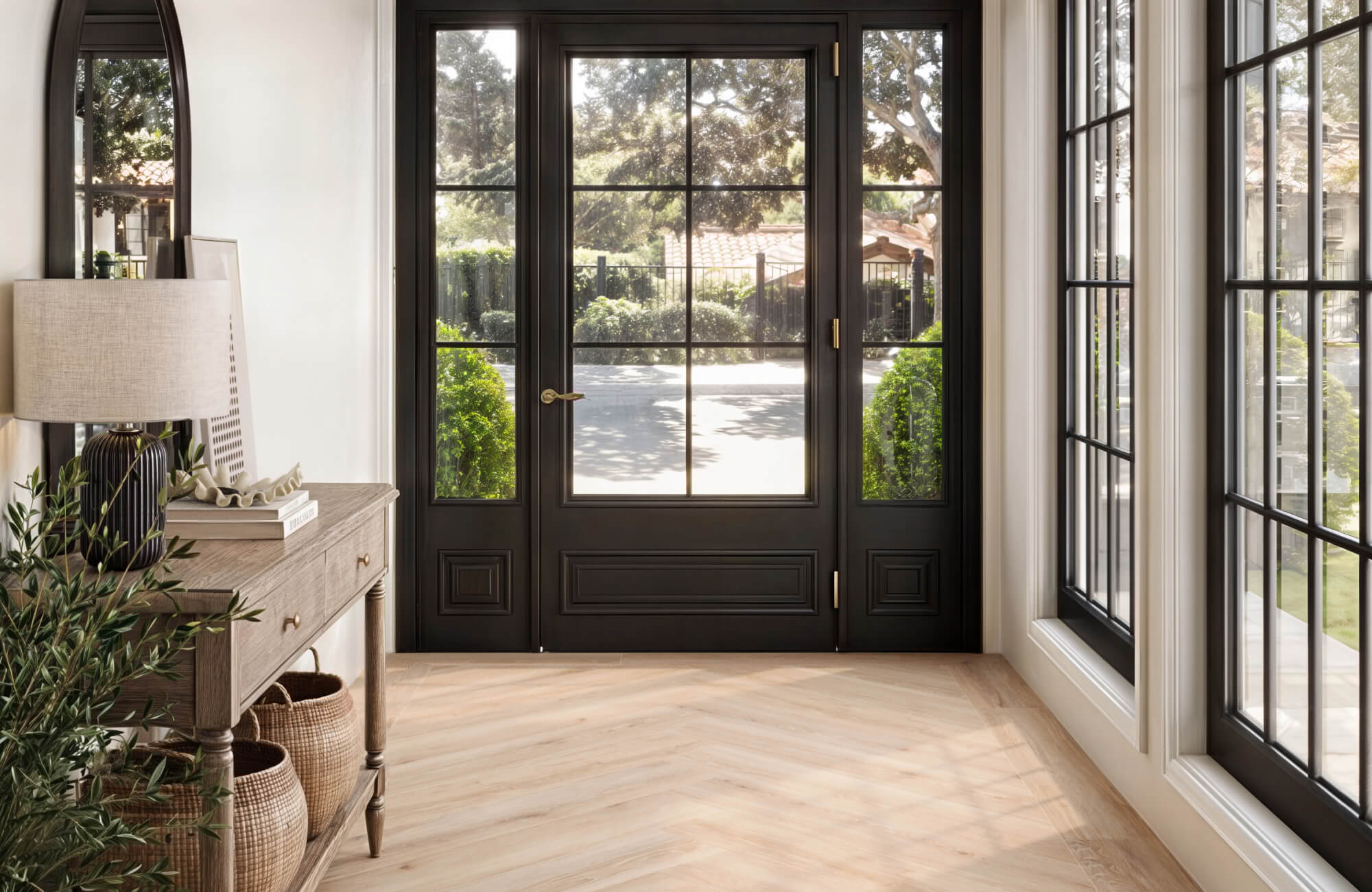 Bright entryway with black framed double doors, sidelights, and light wood-look tile flooring in a clean herringbone pattern.