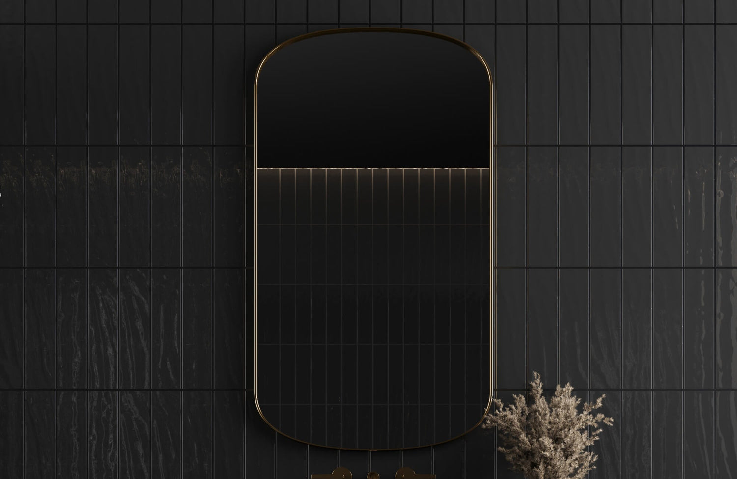 Dark bathroom wall with glossy black vertical subway tiles, a rounded rectangular mirror with gold trim, and dried stems beside a matching gold faucet.