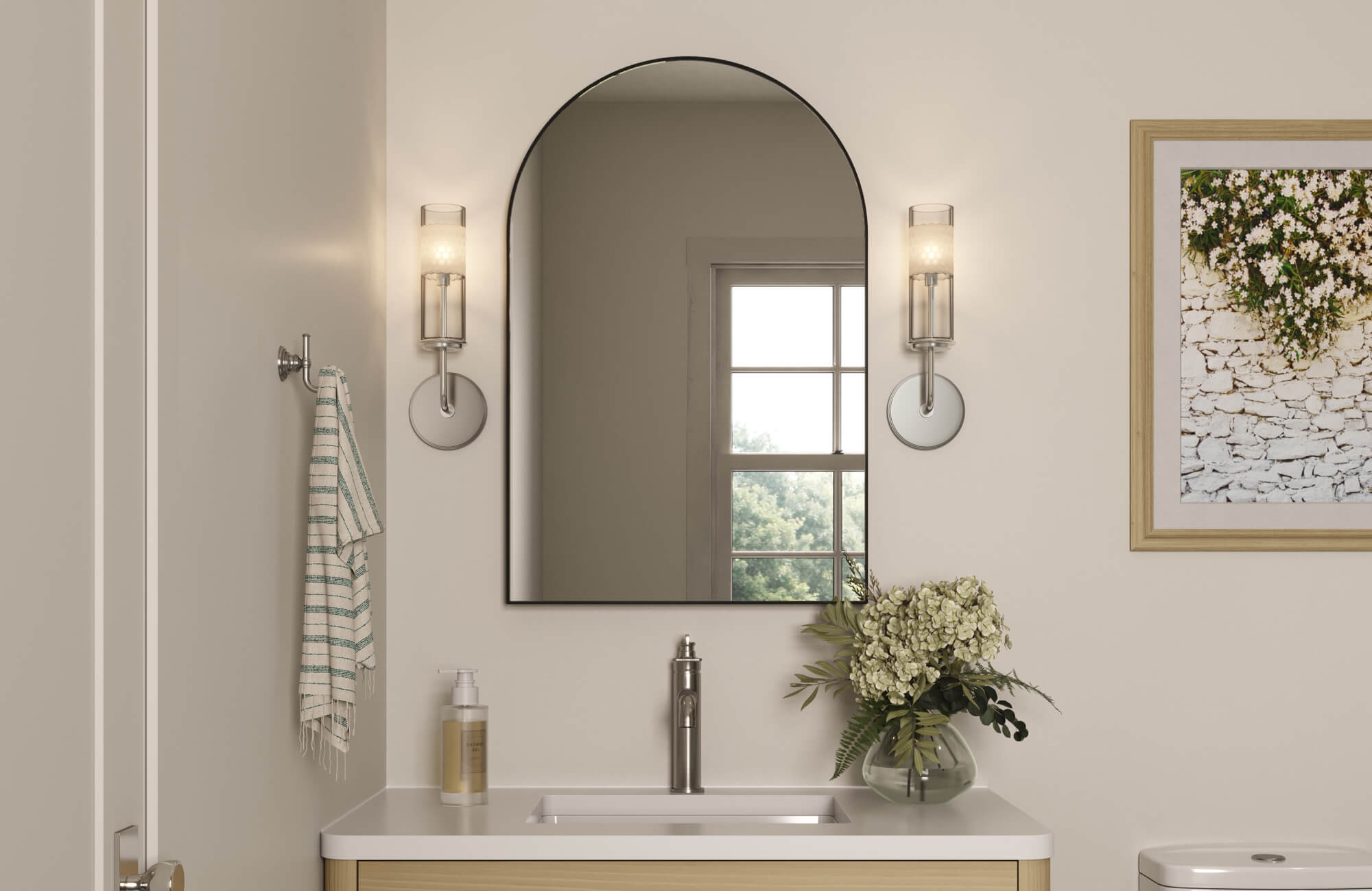 A serene bathroom showcases a large arched mirror centered above a clean, modern vanity, framed by glass-shaded sconces and soft neutral tones that enhance its elegant presence.