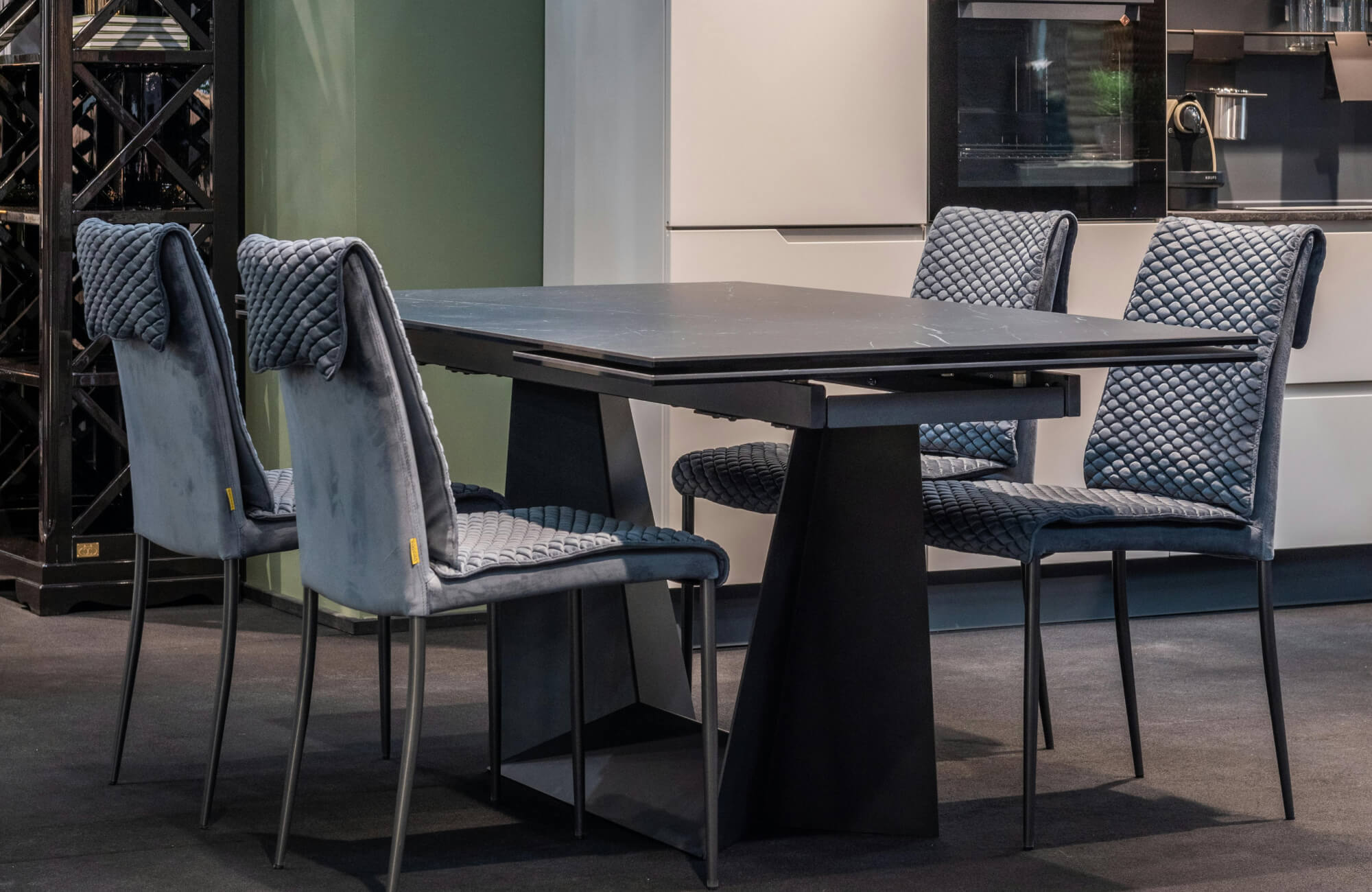 Modern dining setting showcasing a plush, quilted dining chair upholstered in soft gray fabric, paired with a sleek black dining table to create a refined, contemporary atmosphere.