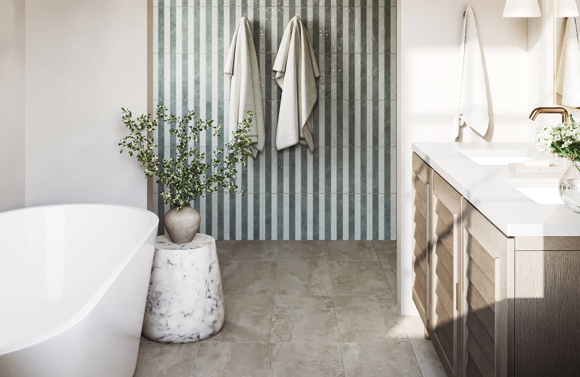 Small bathroom with freestanding tub, green vertical subway tile accent wall, marble stool, wood vanity, and beige cement look tile flooring.