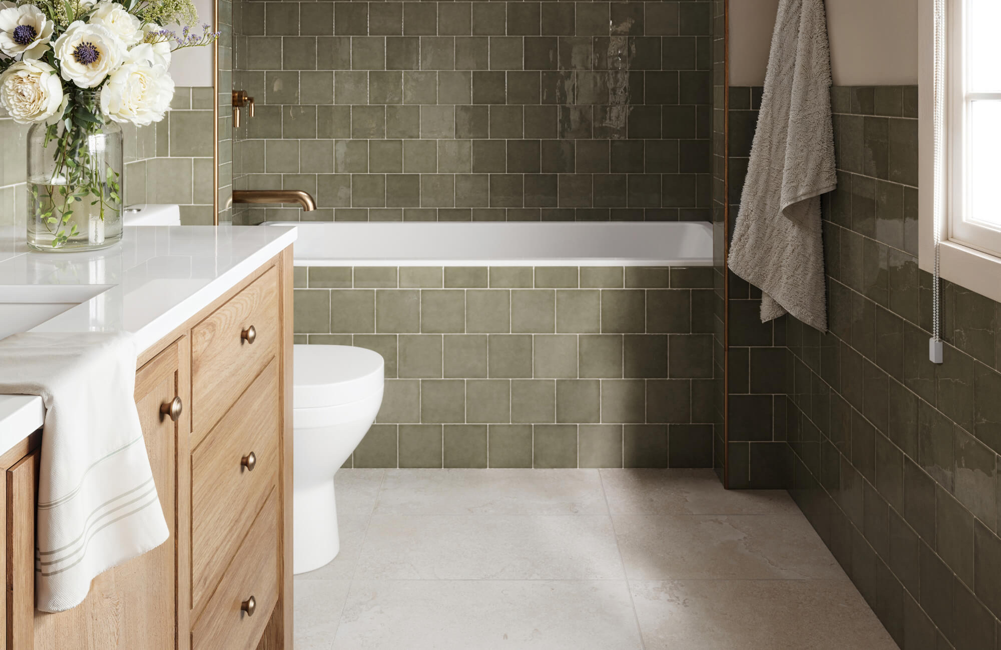 Stylish bathroom featuring earthy green square wall tiles and large format floor tiles that create a spacious, open feel. Warm wood cabinetry adds a cozy touch.