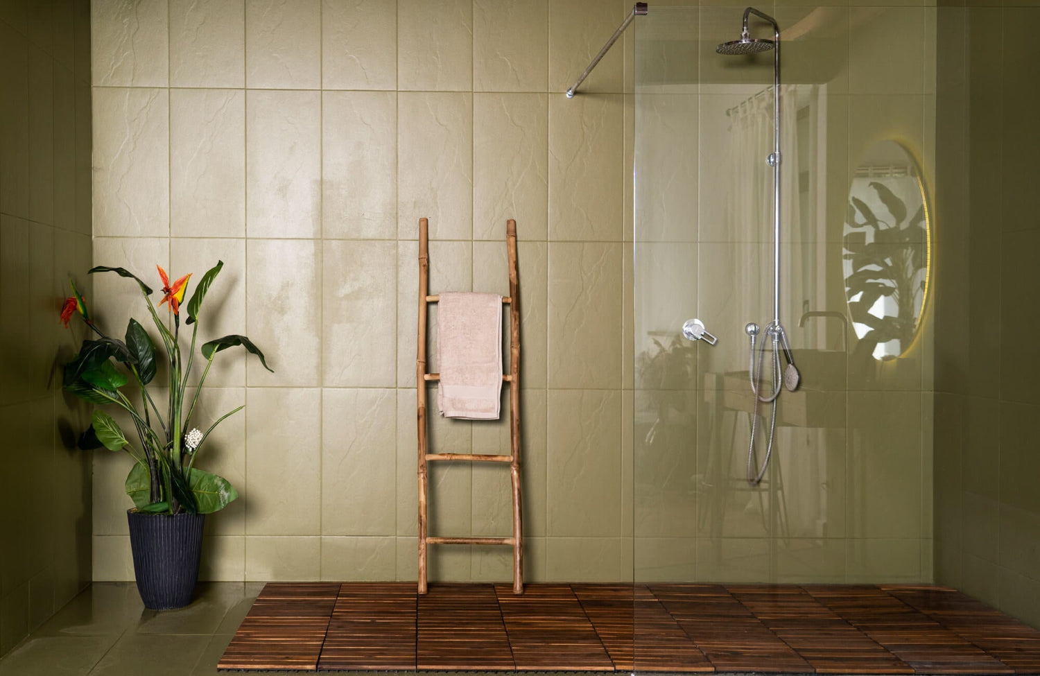 Spa-inspired shower with large matte olive green wall tiles, wood flooring, a rainfall showerhead, and warm wood accents, creating a serene, nature-inspired retreat.