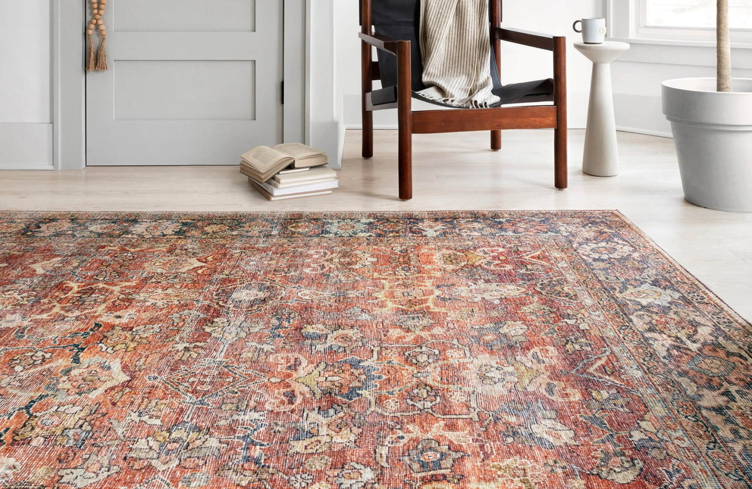 A vintage-inspired rug in warm rust and navy tones anchors a cozy reading nook with mid-century accents and soft natural light.