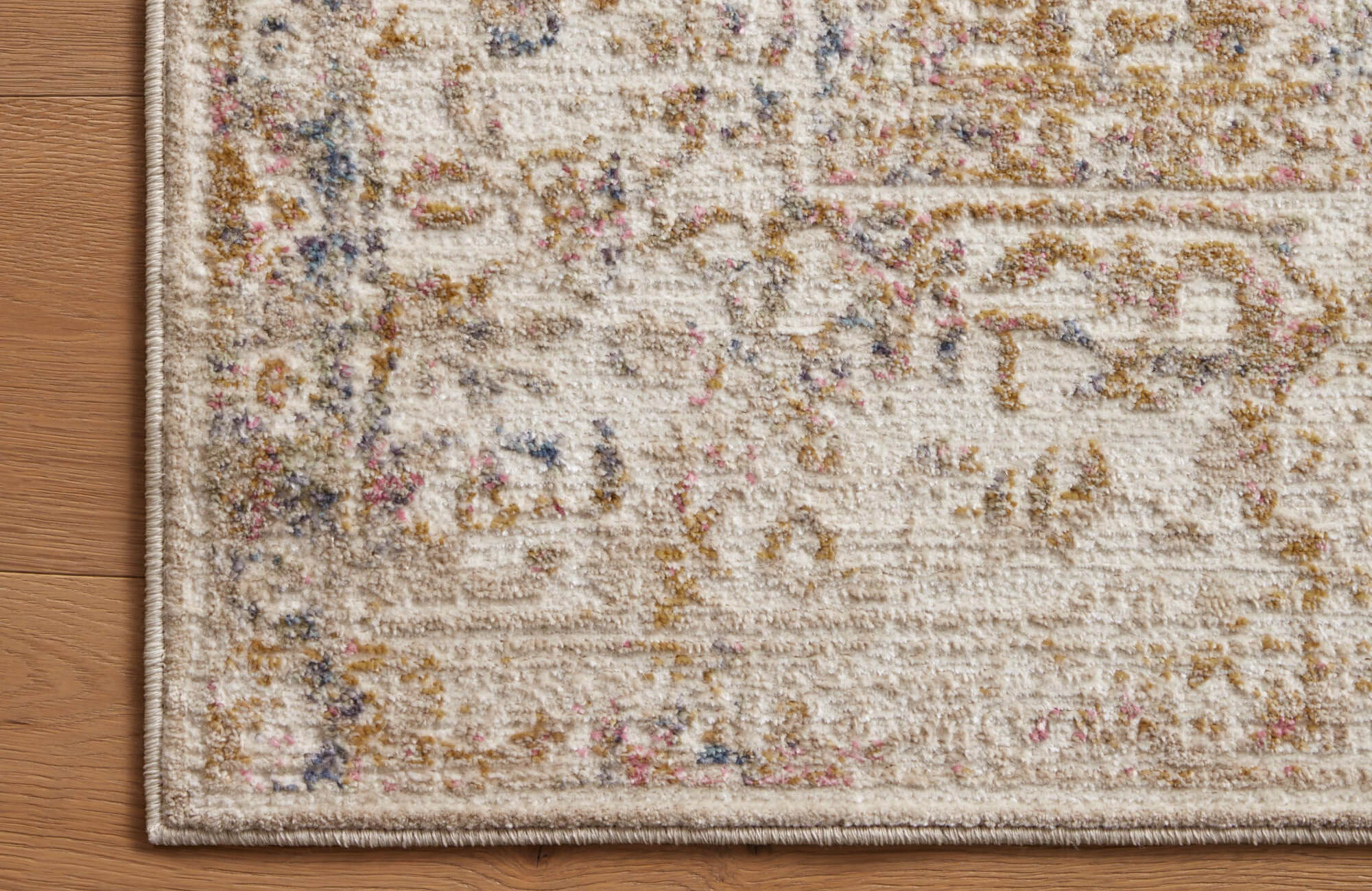 Distressed polypropylene and polyester rug in cream with hints of gold, pink, and blue, blending vintage charm with modern durability.