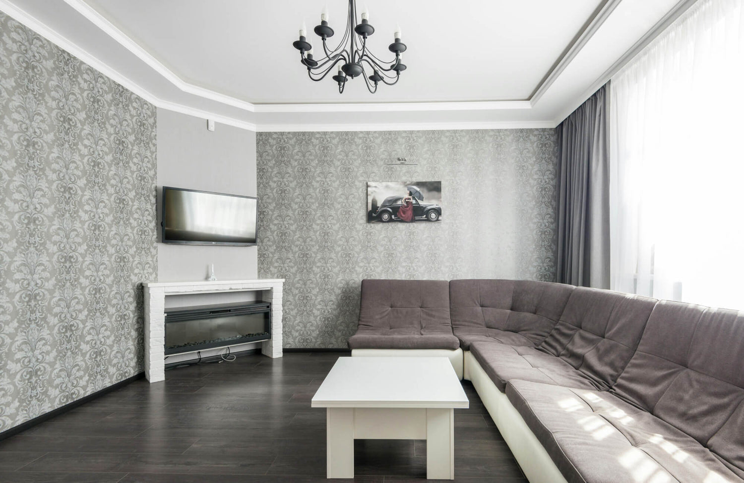 Light gray patterned wallpaper adds subtle elegance and softness to this modern living room with dark flooring.