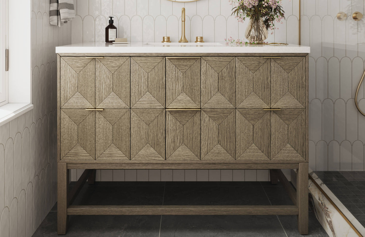 Geometric wood vanity with brass hardware stands out against scalloped wall tiles and dark stone flooring in this stylish bathroom.