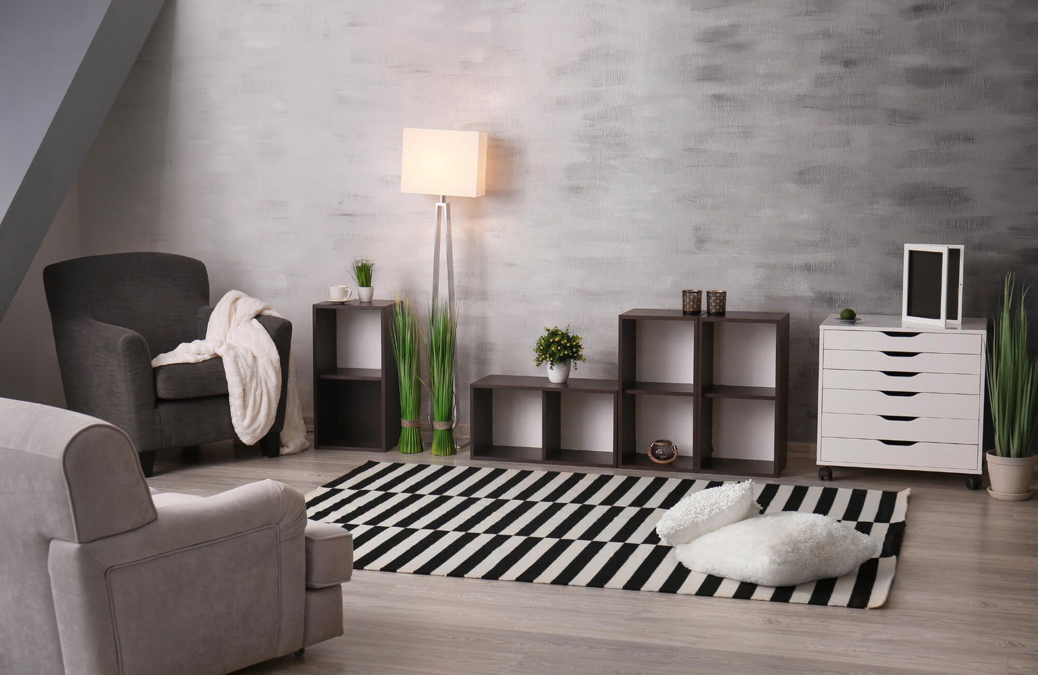 Modern living room with a black-and-white striped rug, cozy armchairs, open shelving, and decorative plants, creating a stylish, inviting space.