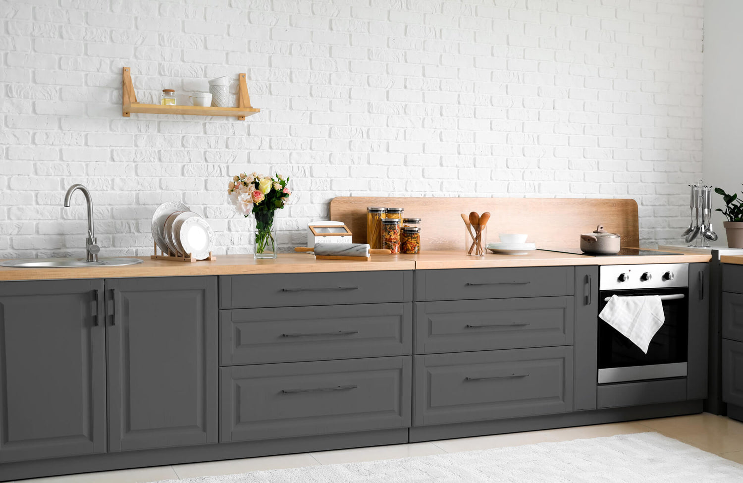 Modern kitchen interior with gray cabinets, wood countertops, and a white brick subway tile backsplash under open shelving.
