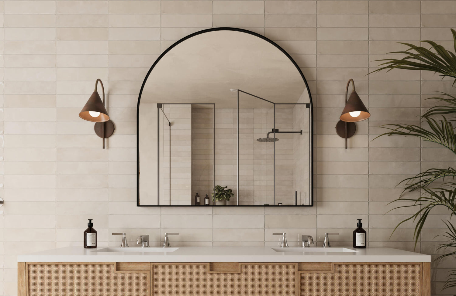 Bathroom with a large arched mirror, wall-mounted sconces, and neutral ceramic wall tiles, highlighting ideal mirror placement